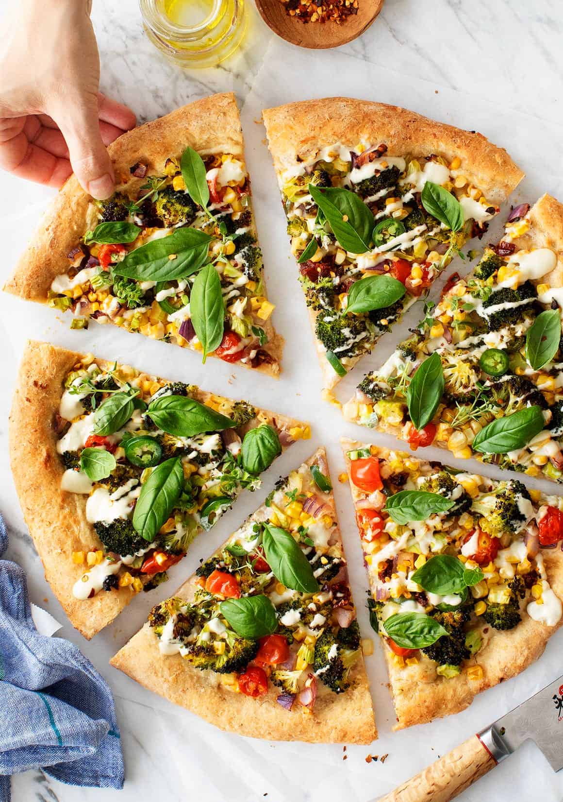 Hand grabbing a slice of vegan pizza