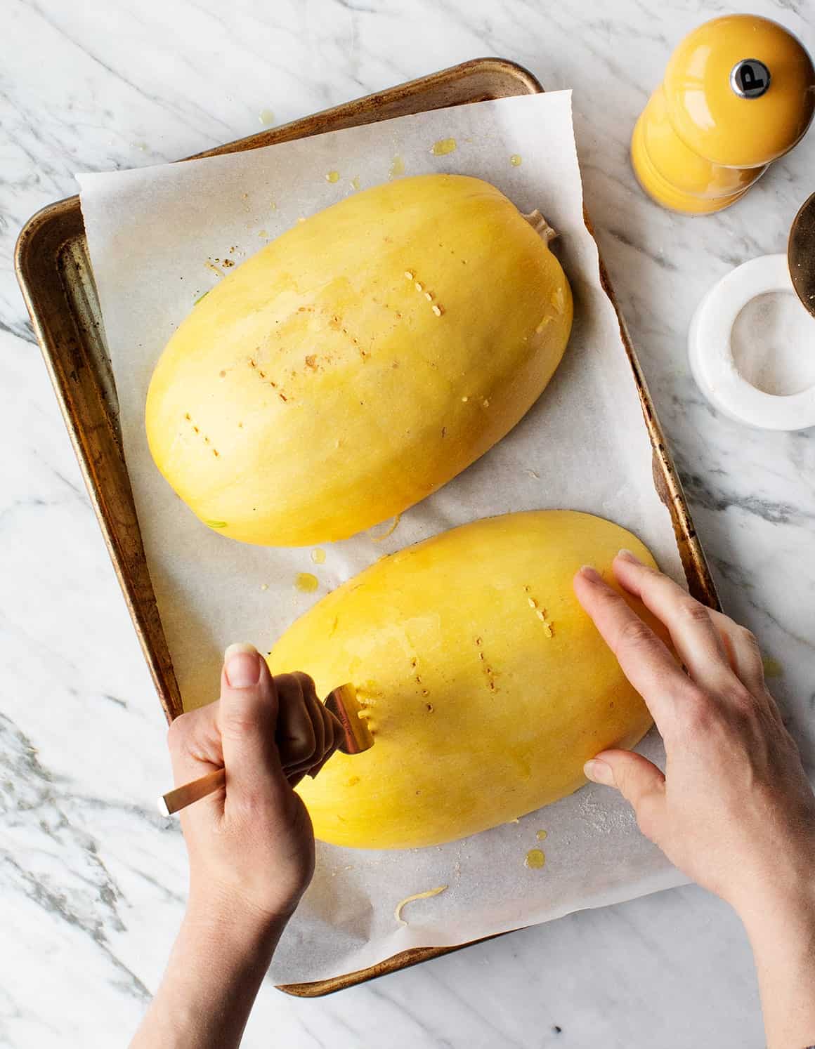 Hands poking holes in Spaghetti Squash with a fork