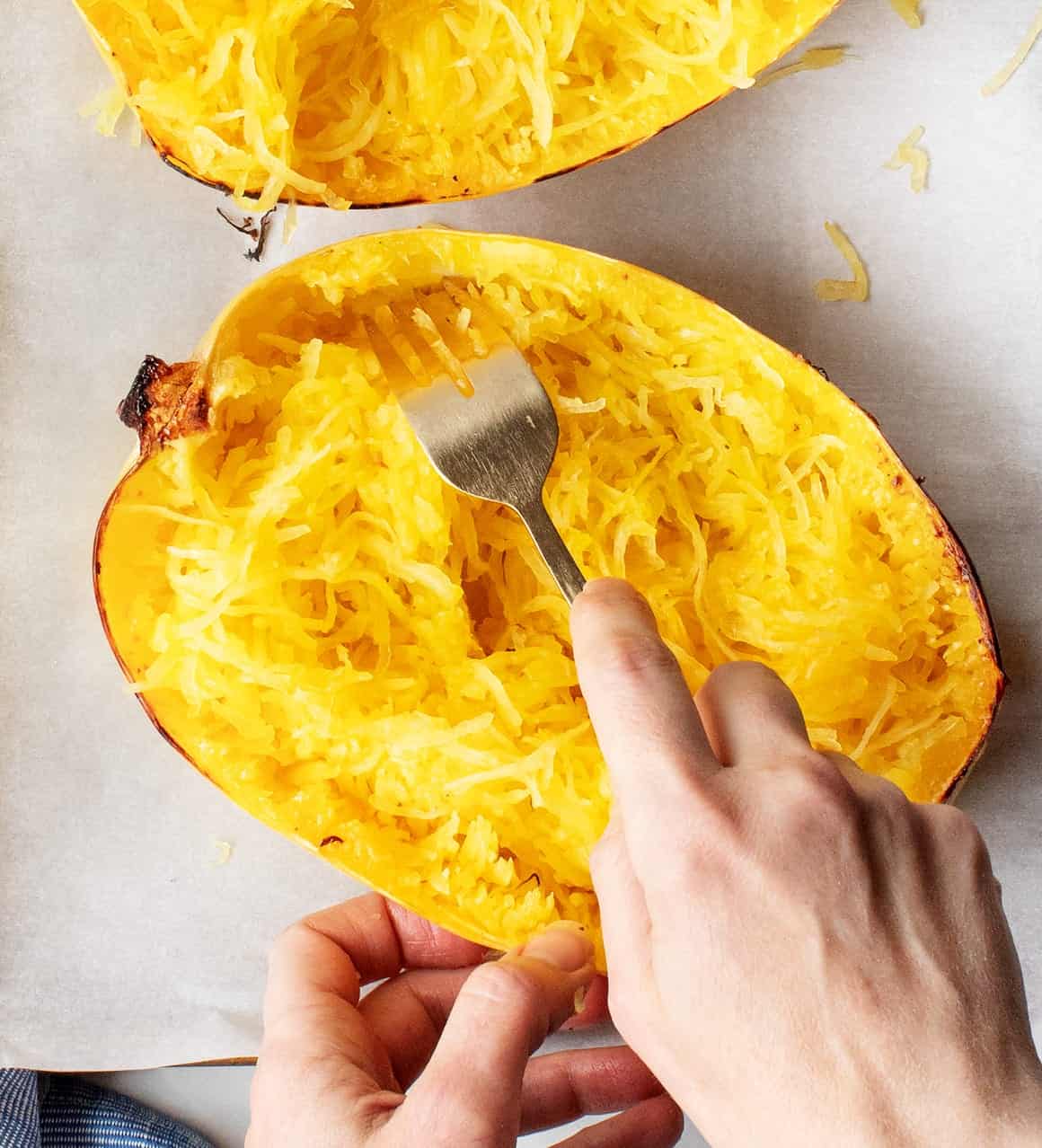 Hands fluffing Spaghetti Squash strands with fork