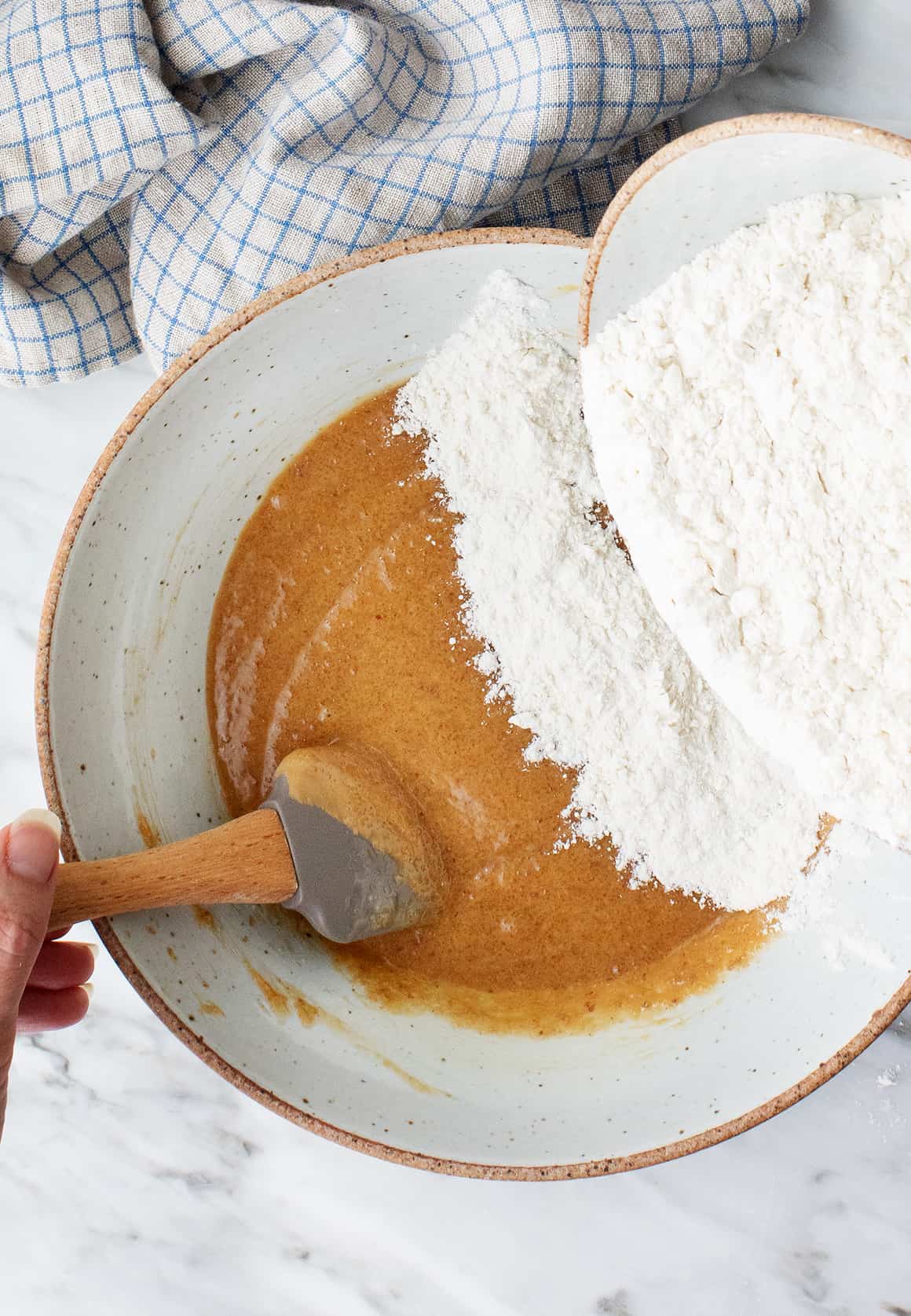 Adding dry ingredients to wet ingredients in a mixing bowl