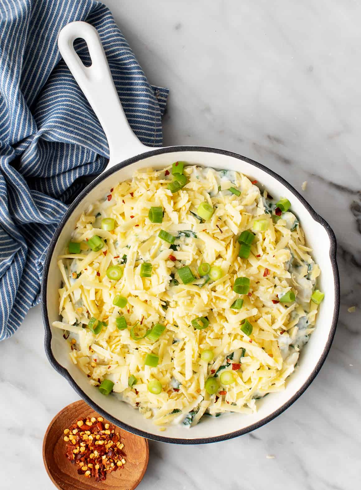 Grated cheese on top of dip in a skillet