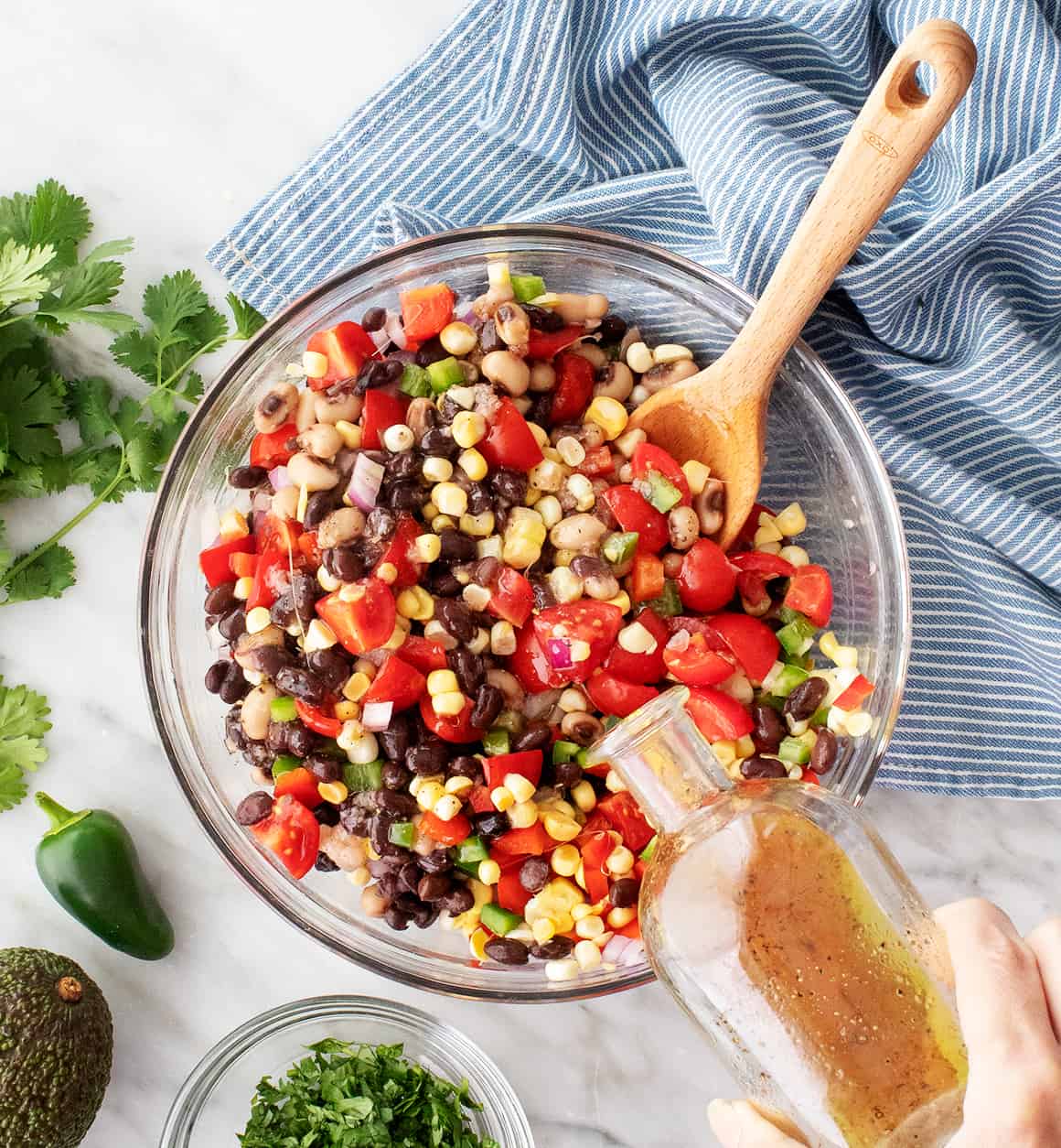 Pouring dressing over black bean and corn salsa