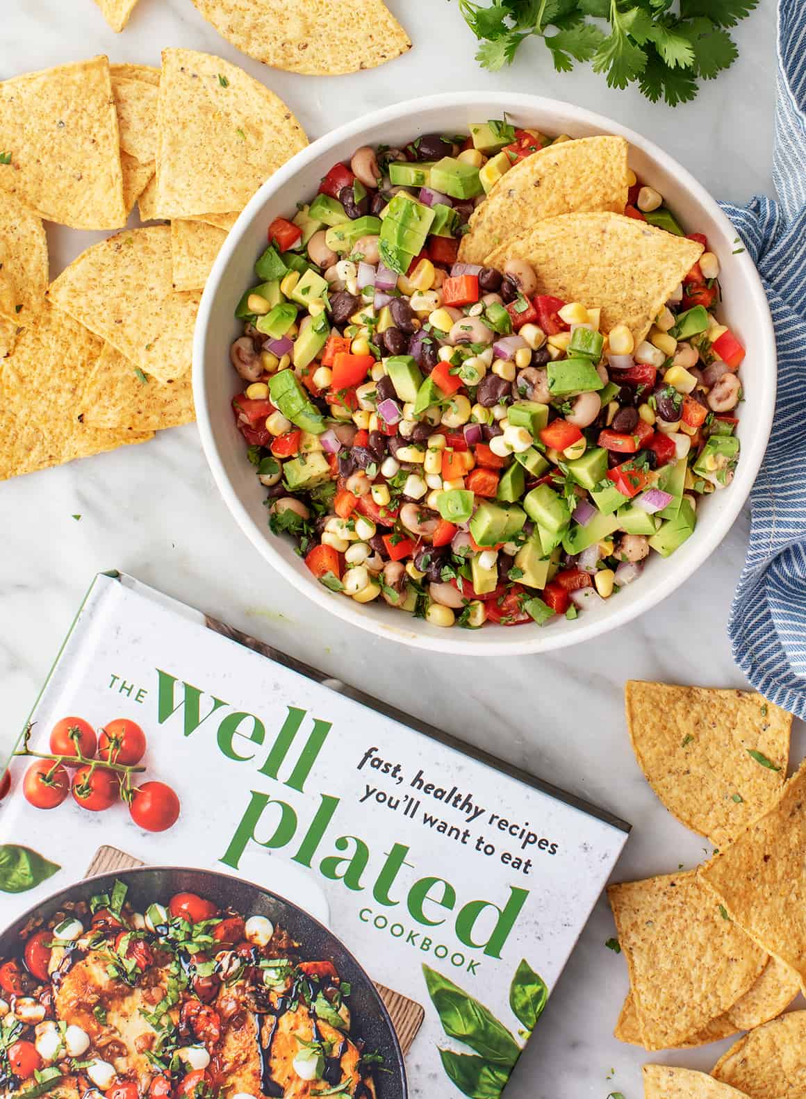 The Well Plated Cookbook with a bowl of Texas Caviar