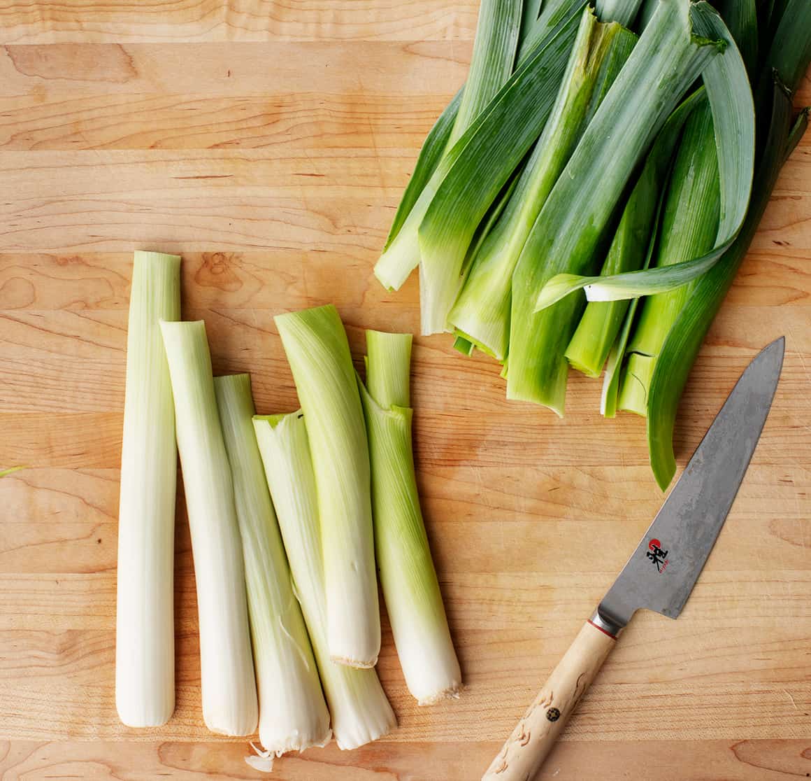 Dark green tops separated from white and light green parts on a cutting board