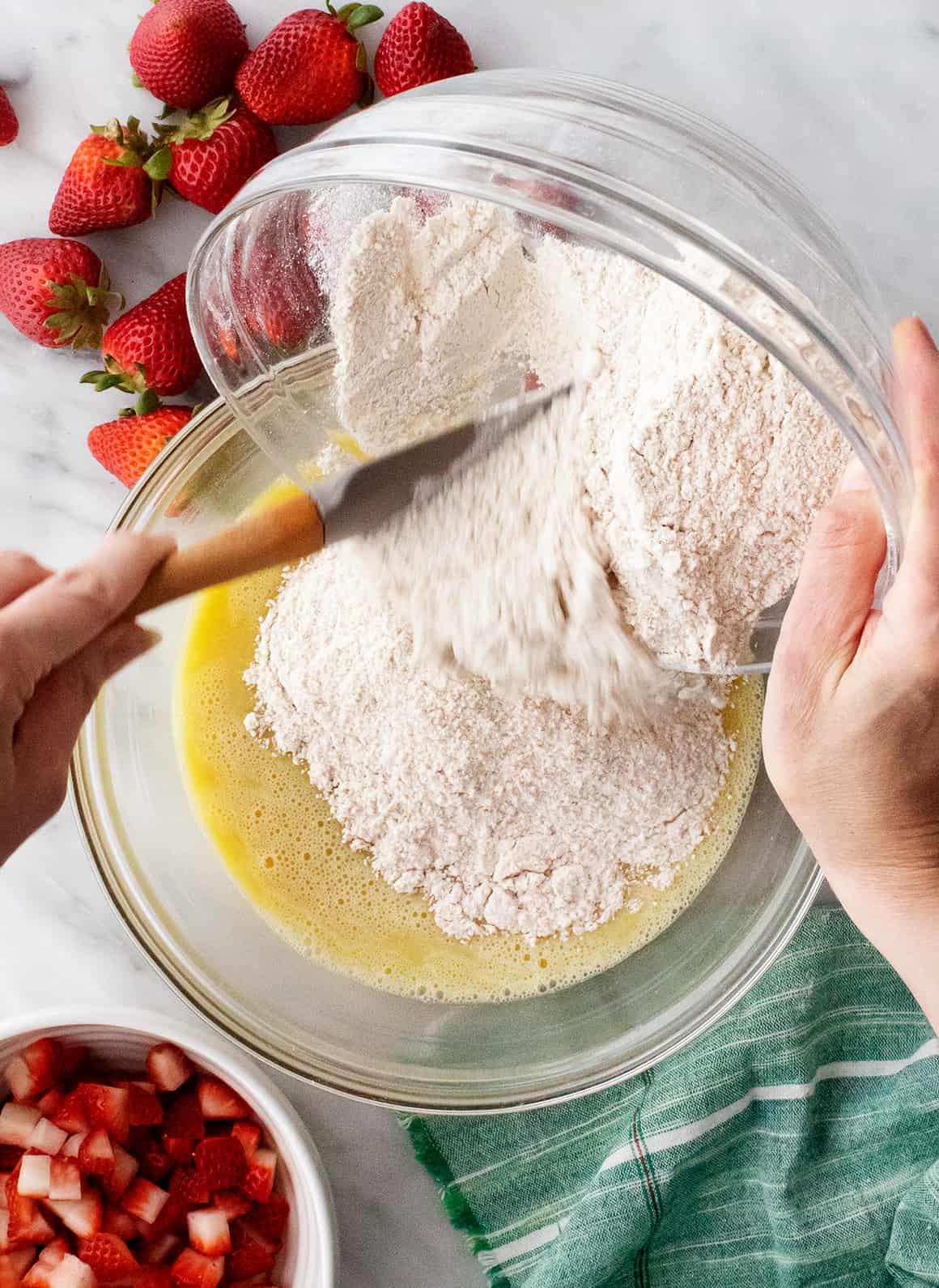 Pouring dry ingredients into bowl of wet ingredients