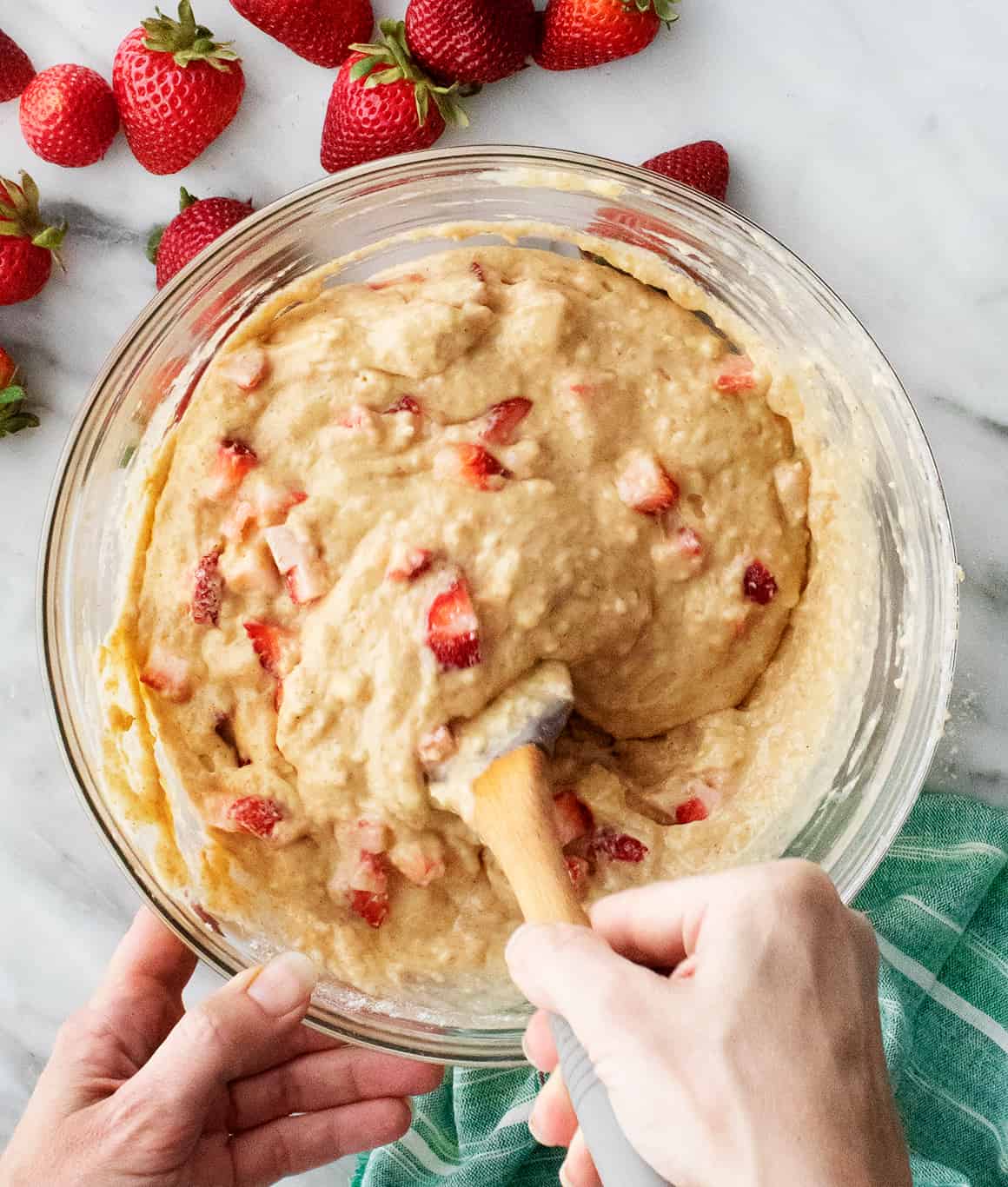 Hand mixing strawberry muffins batter with rubber spatula