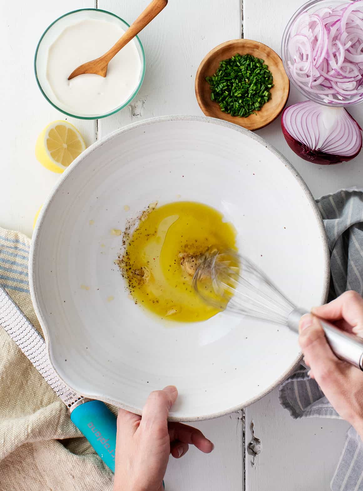 Hand whisking dressing at the bottom of a large bowl