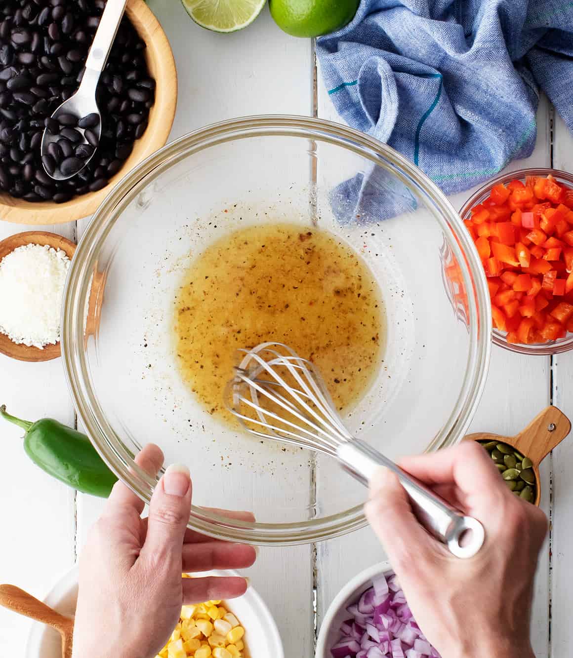 Hand using whisk to mix dressing at the bottom of a bowl