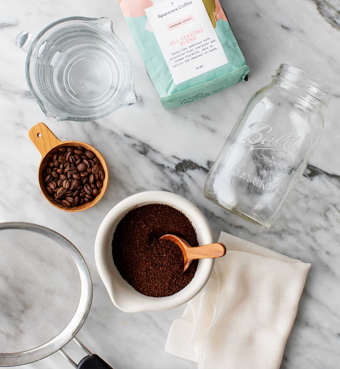 Mason jar, water, strainer, and coffee on marble