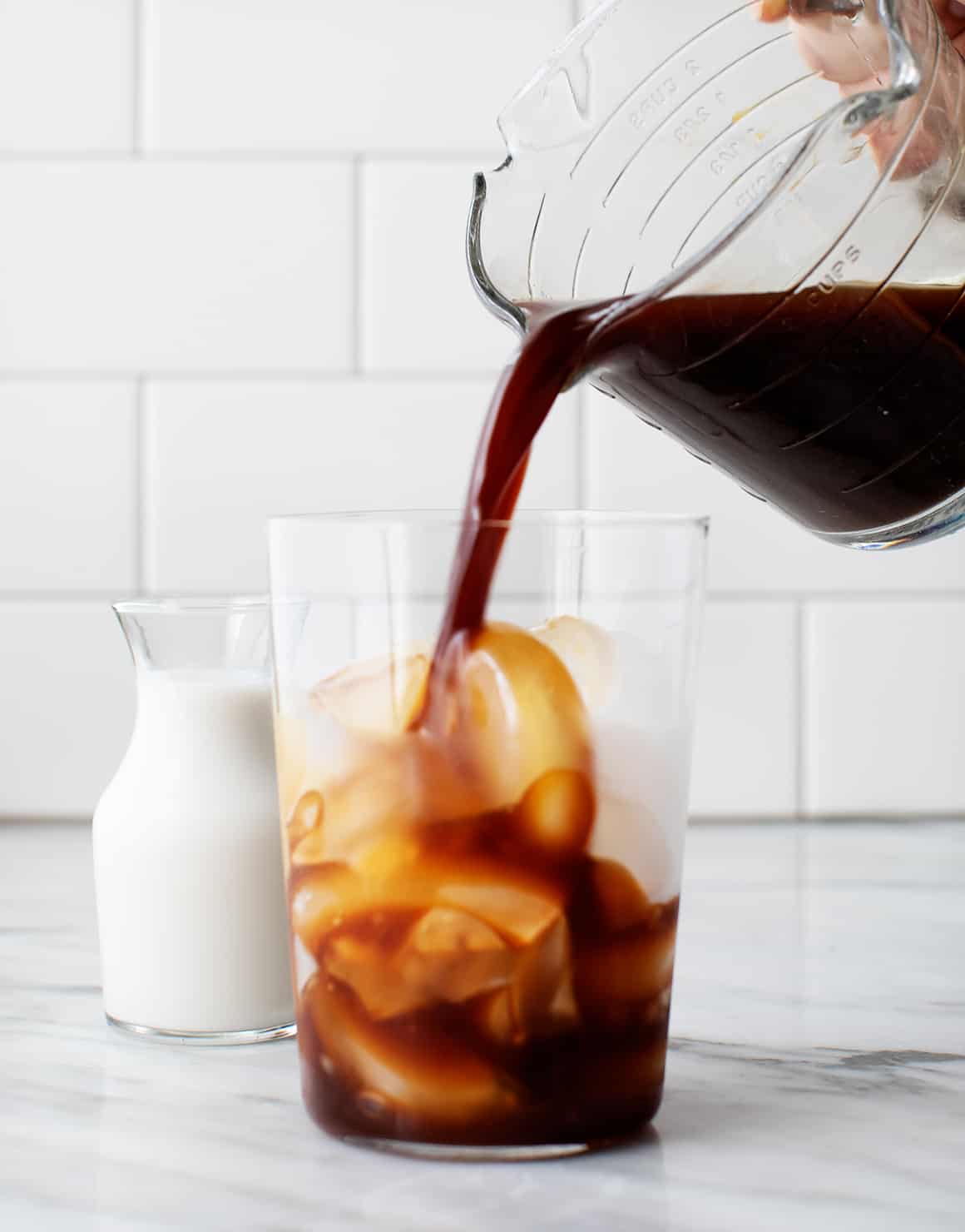 Pouring cold brew coffee into glass with ice