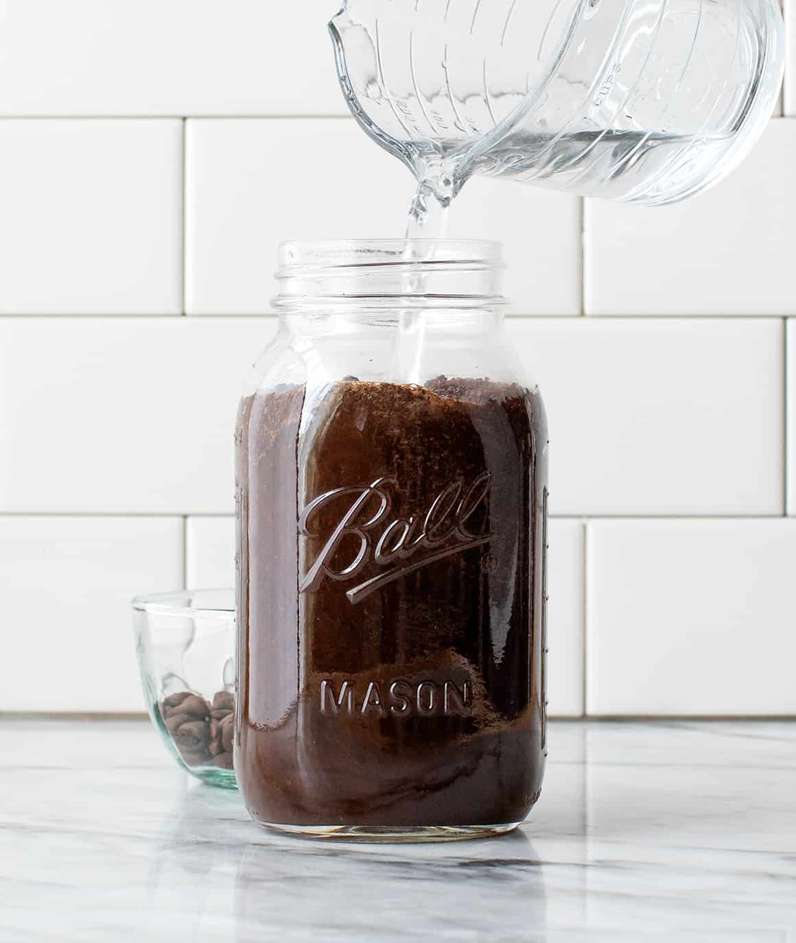 Pouring water over coffee ground in a Mason jar