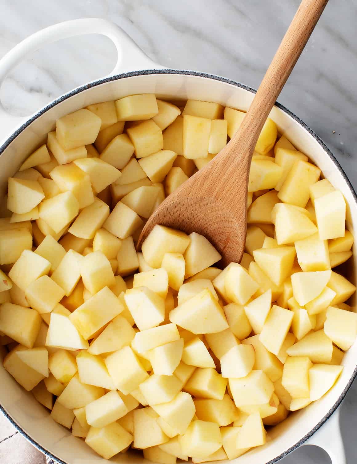 Chopped apples in saucepan with wooden spoon