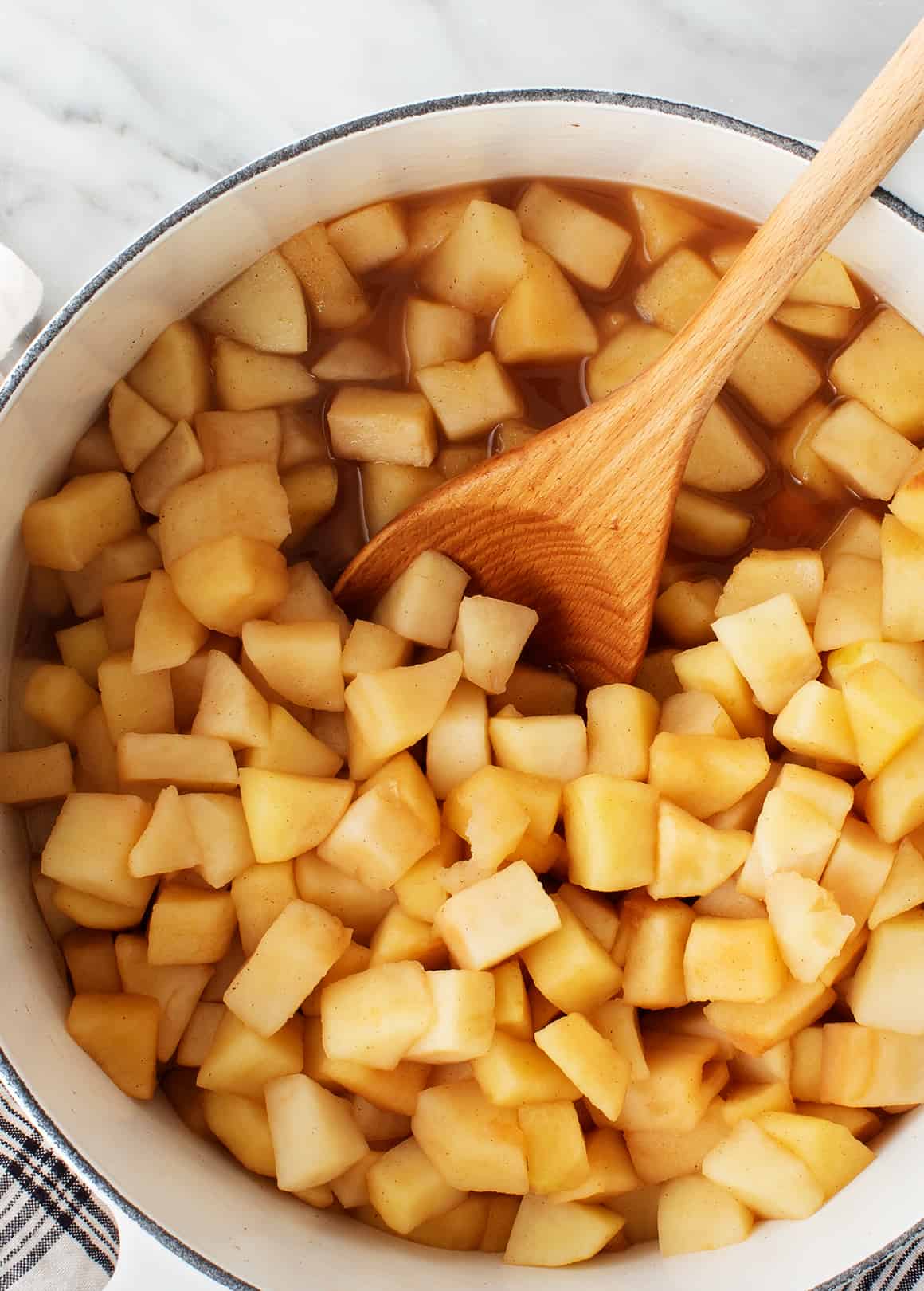 Stewed chopped apples in saucepan with wooden spoon