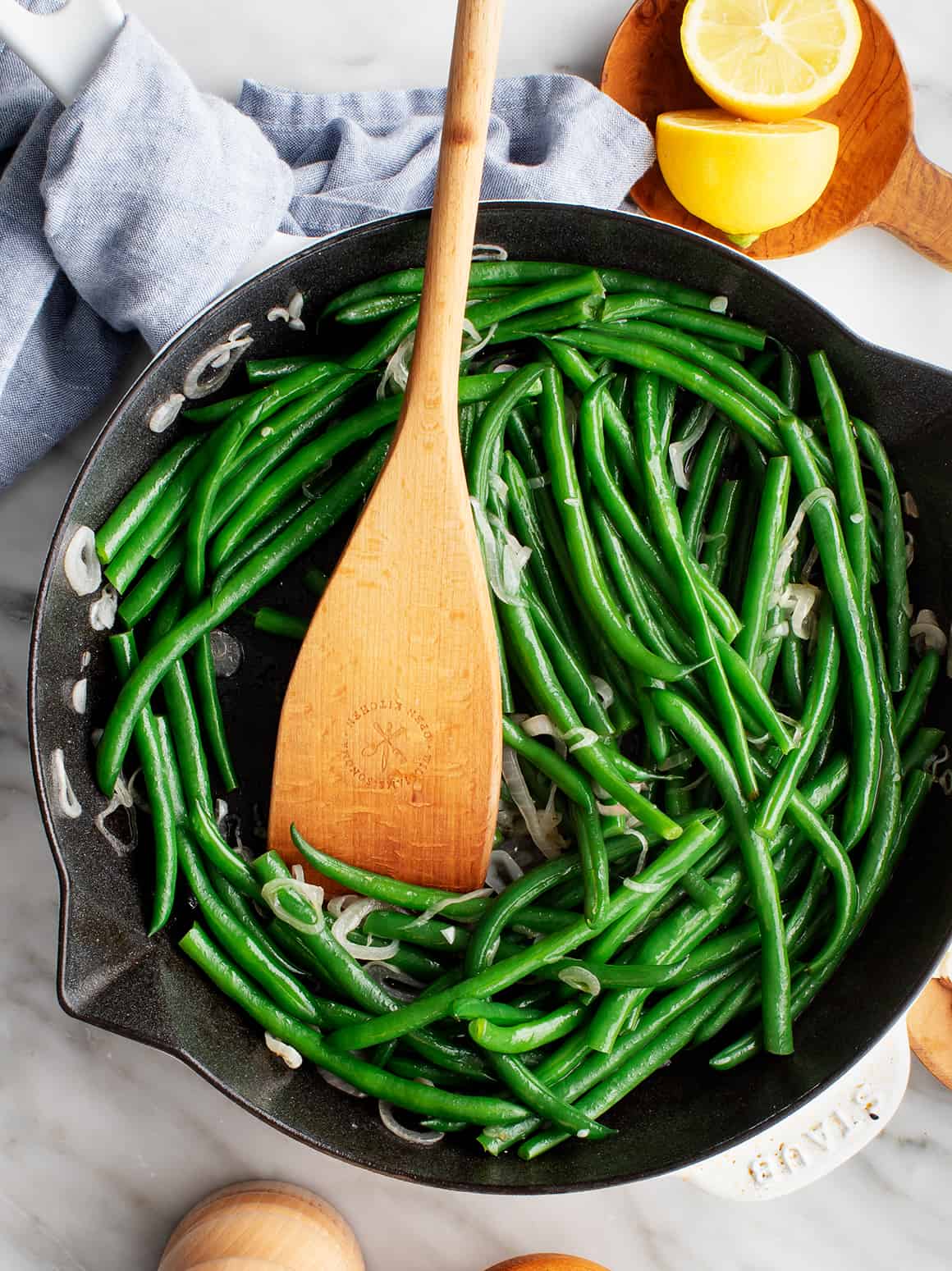 Green beans in a skillet with wooden spatula