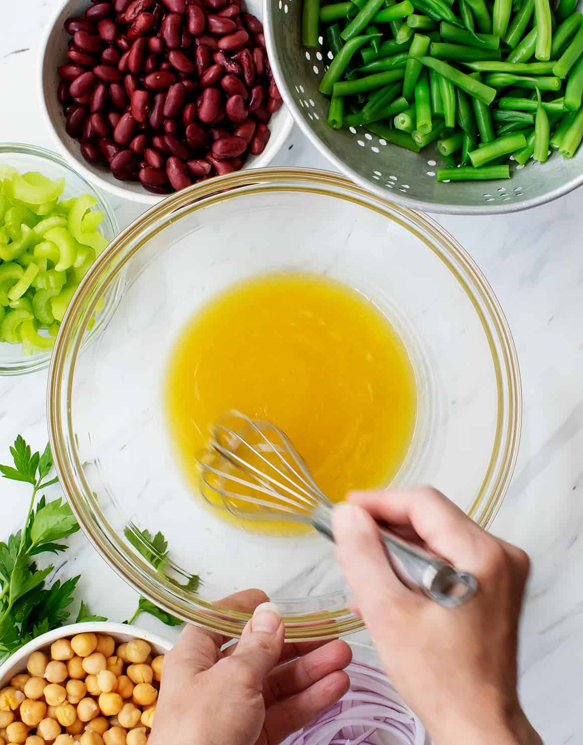 Hand whisking dressing at the bottom of a large bowl