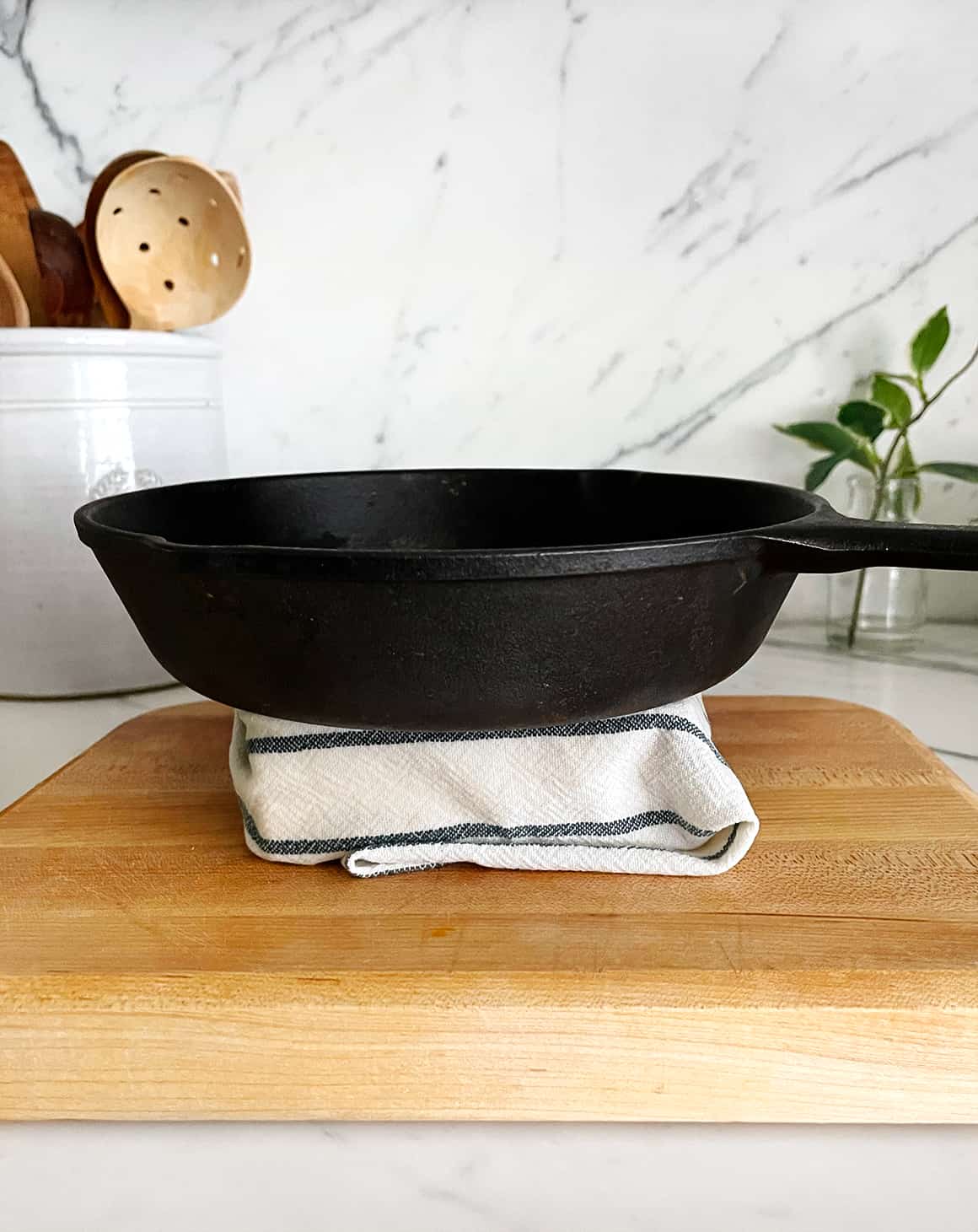 Cast iron skillet on top of block of tofu wrapped in a kitchen towel