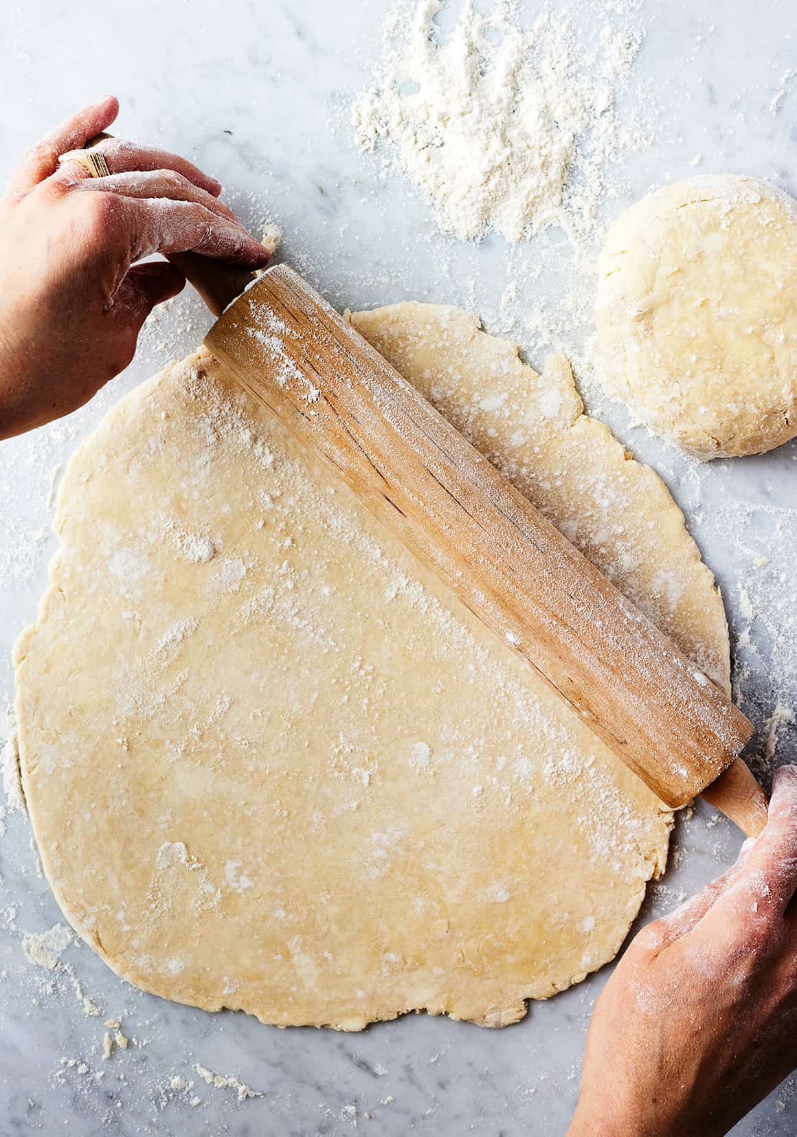 Hands using rolling pin to roll out homemade pie crust
