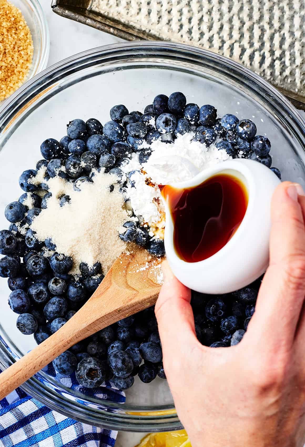 Pouring vanilla over blueberry cobbler filling ingredients