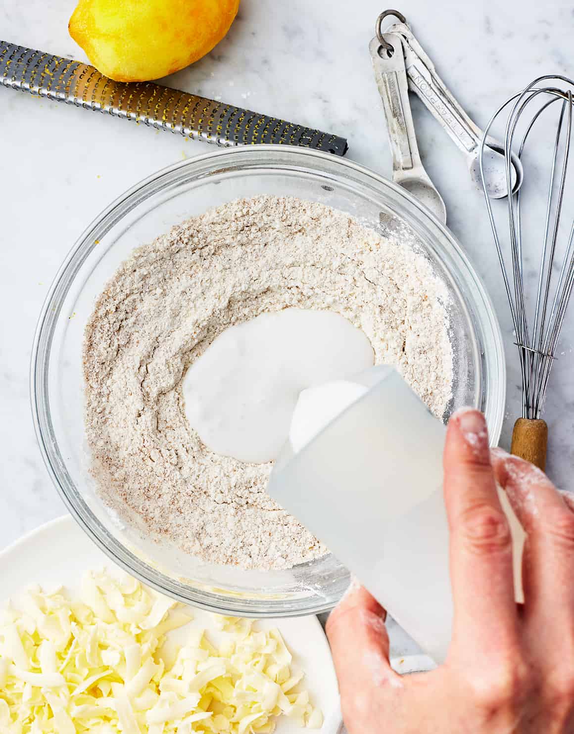 Pouring coconut milk into bowl of flour