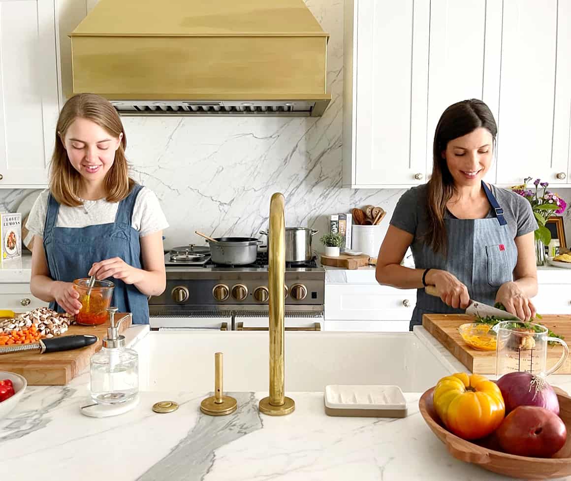 Phoebe whisking sauce and Jeanine chopping cilantro at the kitchen counter