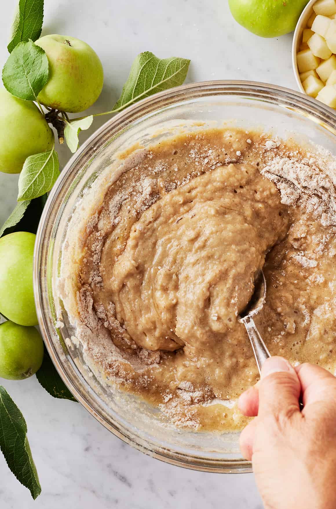 Hand mixing apple muffins batter with spoon