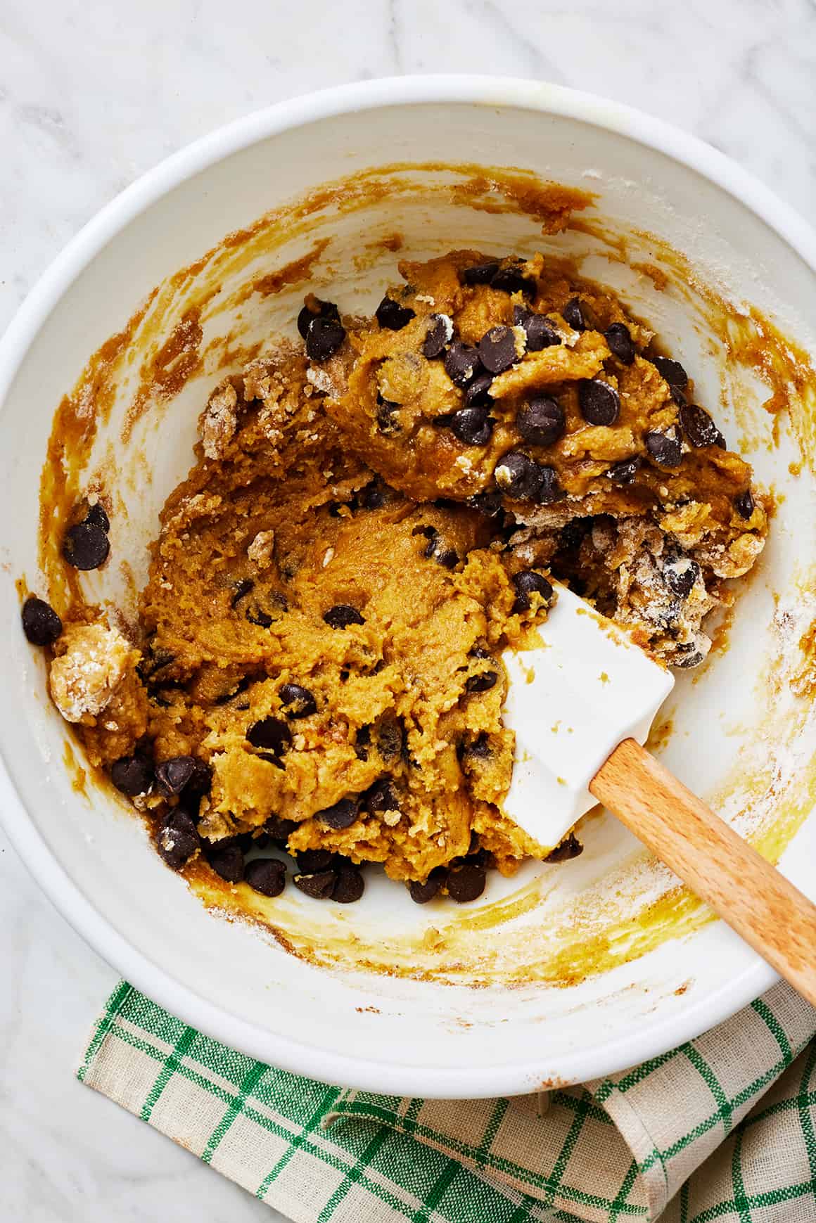 Pumpkin chocolate chip cookie dough in a mixing bowl with rubber spatula