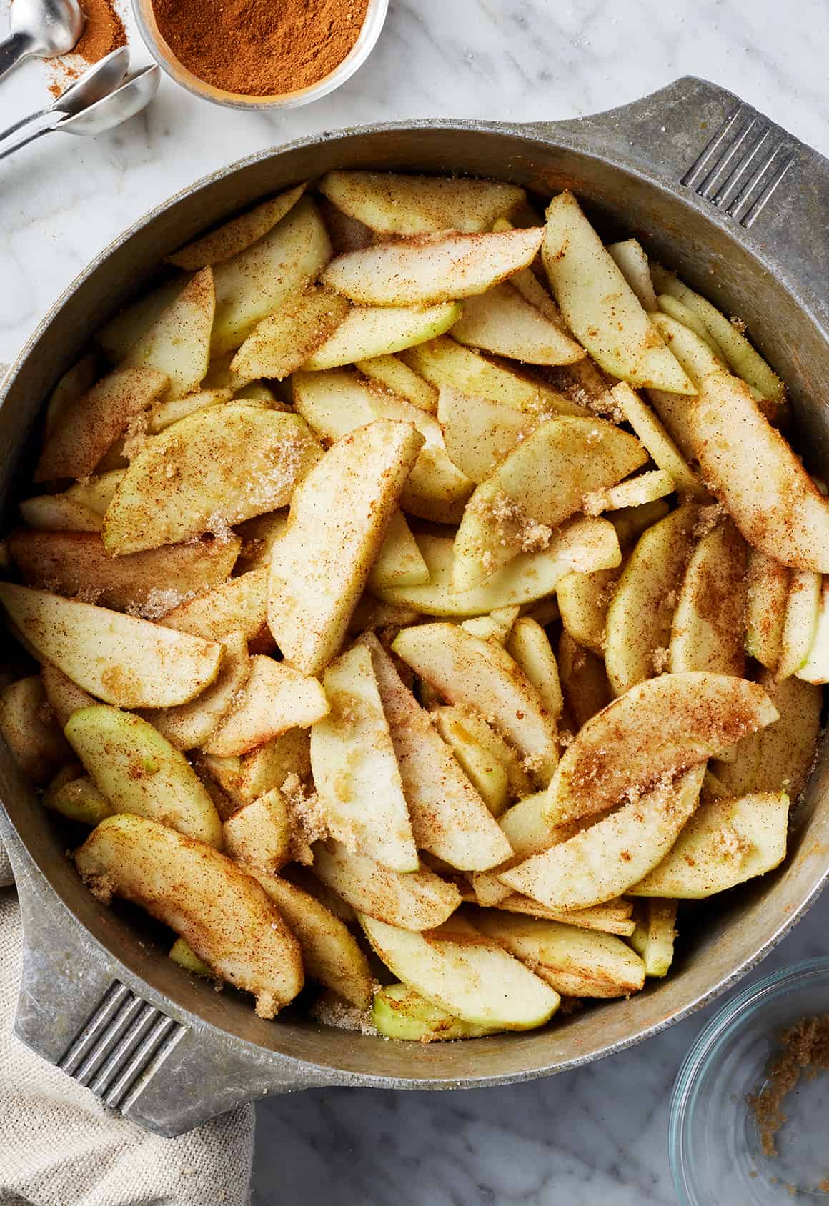 Sliced apples in a pot with cinnamon and sugar