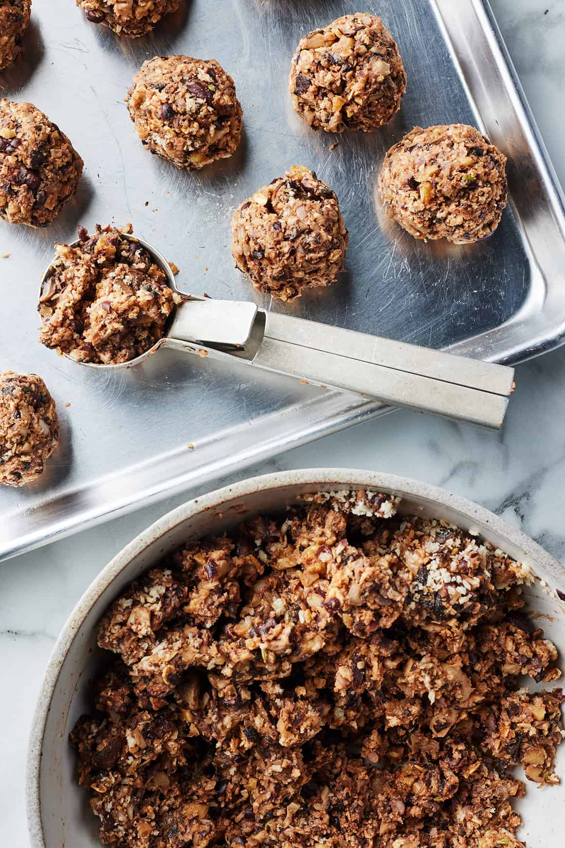 Vegan meatballs on a baking sheet with scoop