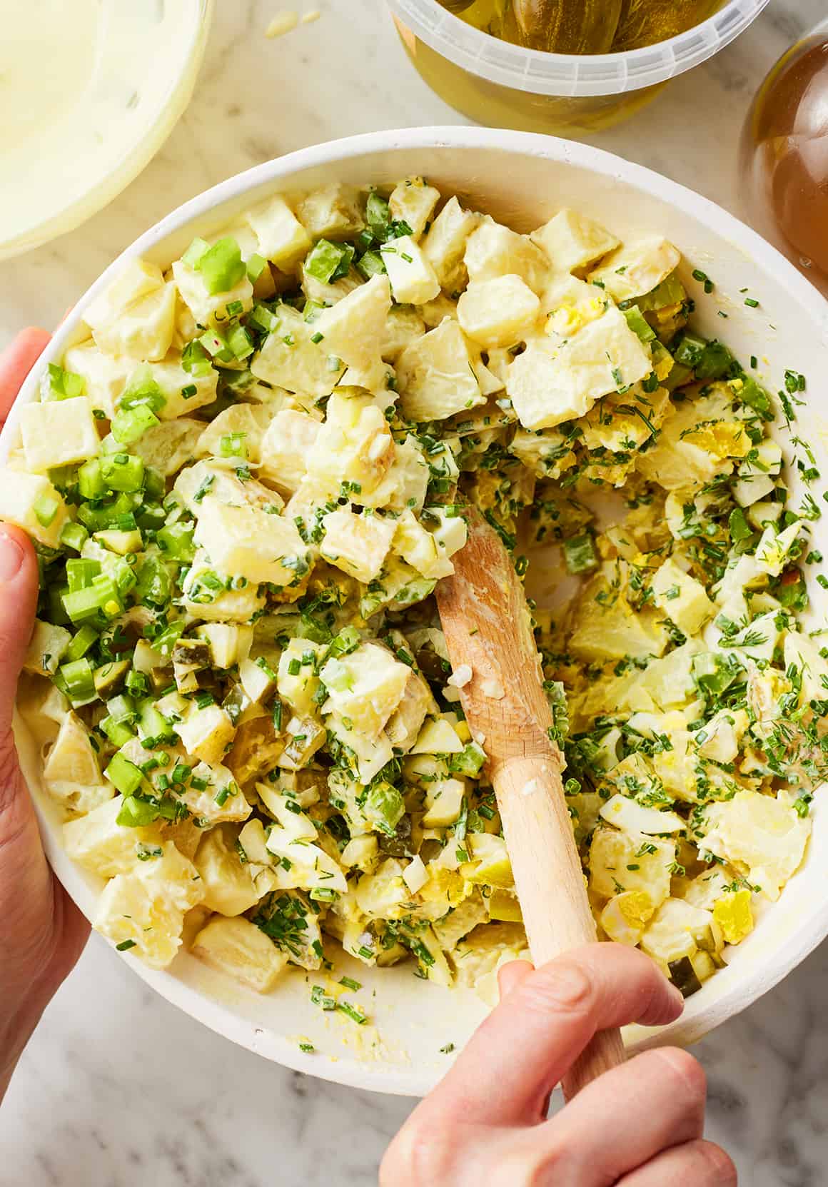 Stirring best potato salad in large bowl