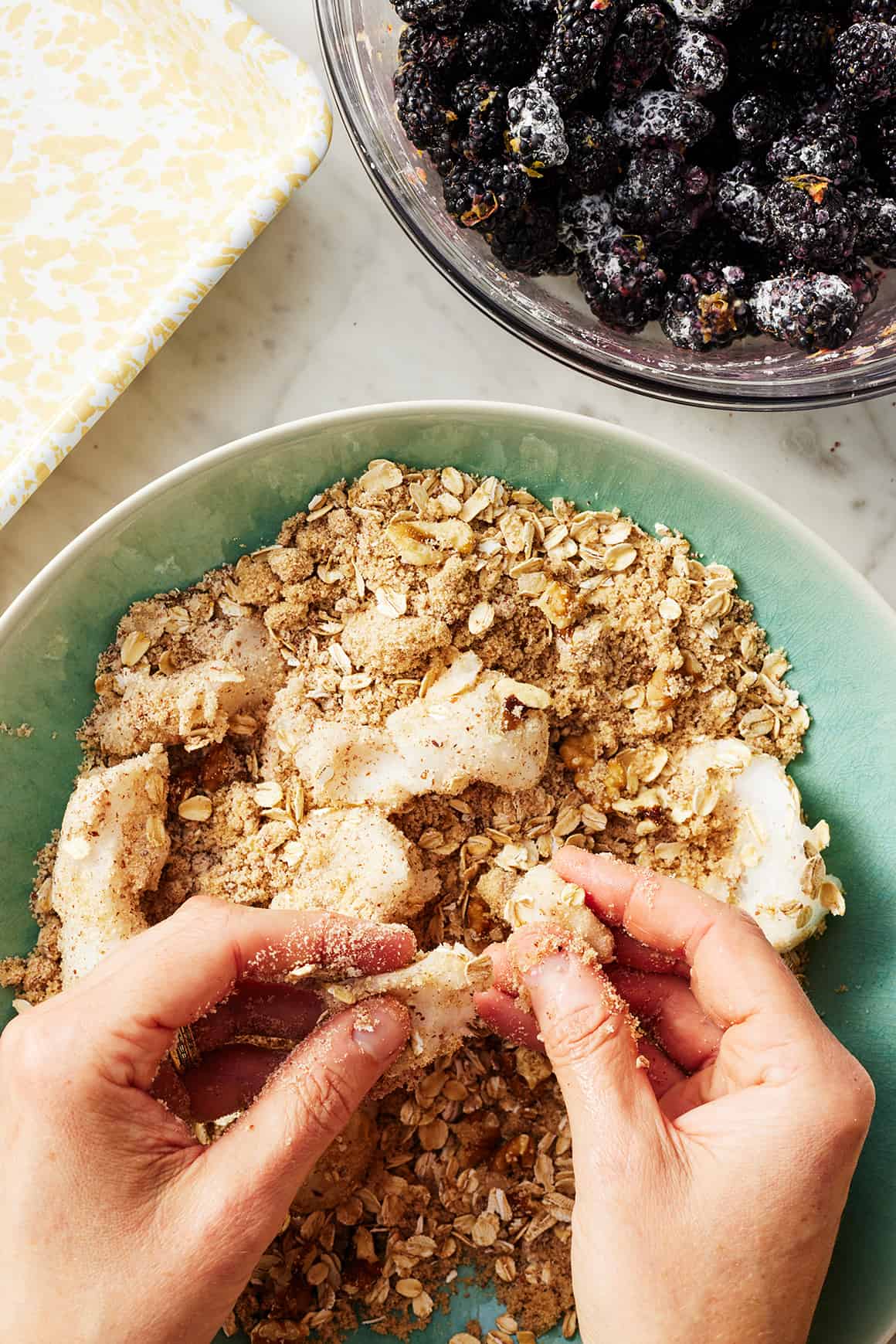 Hands working coconut oil into crumble topping ingredients
