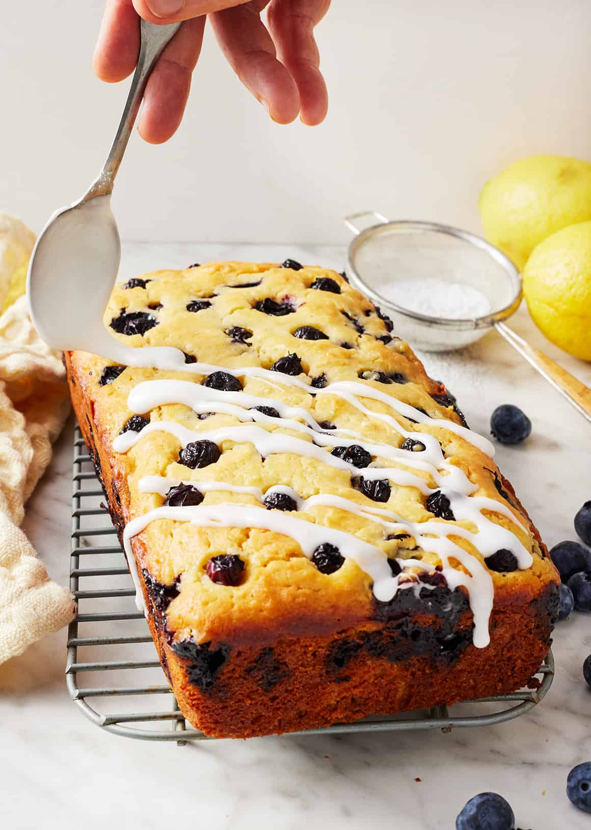 Drizzling lemon glaze over blueberry bread
