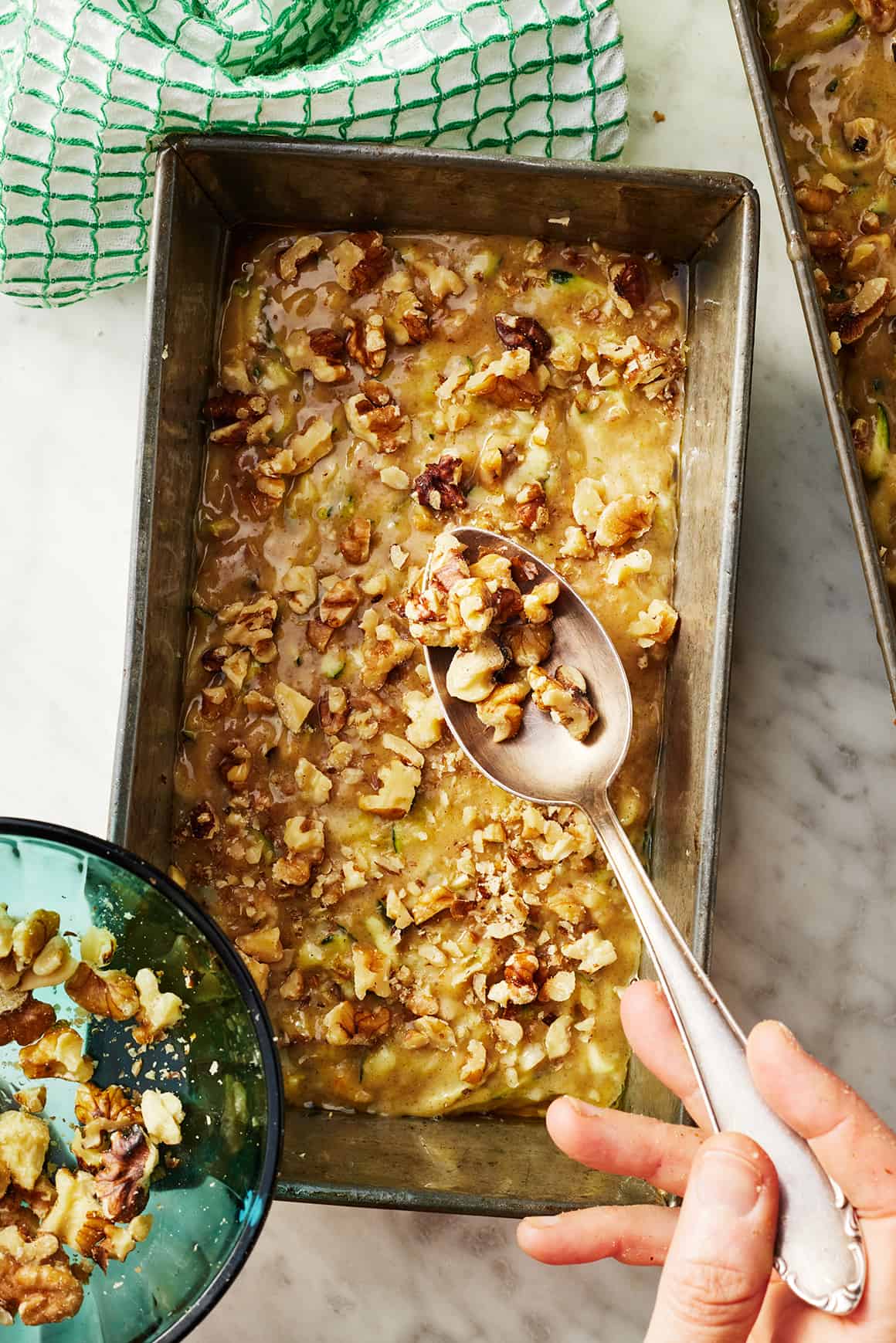 Sprinkling walnuts over zucchini bread before baking