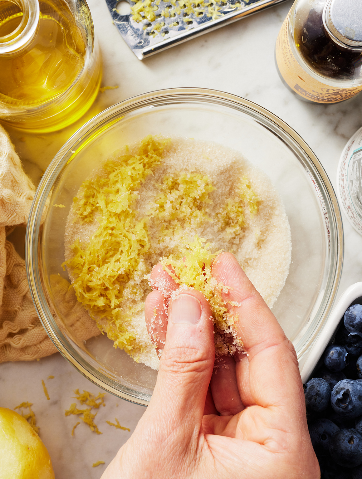 Hand massaging zest into sugar