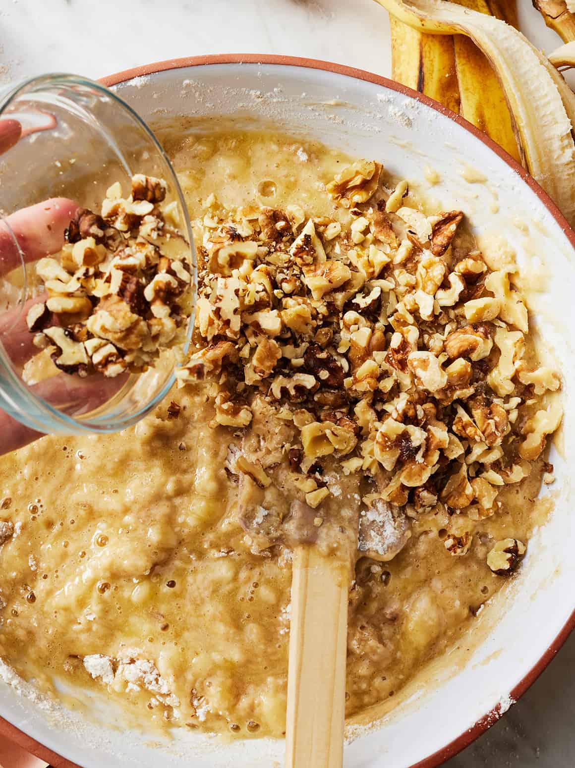 Pouring walnuts into banana bread batter