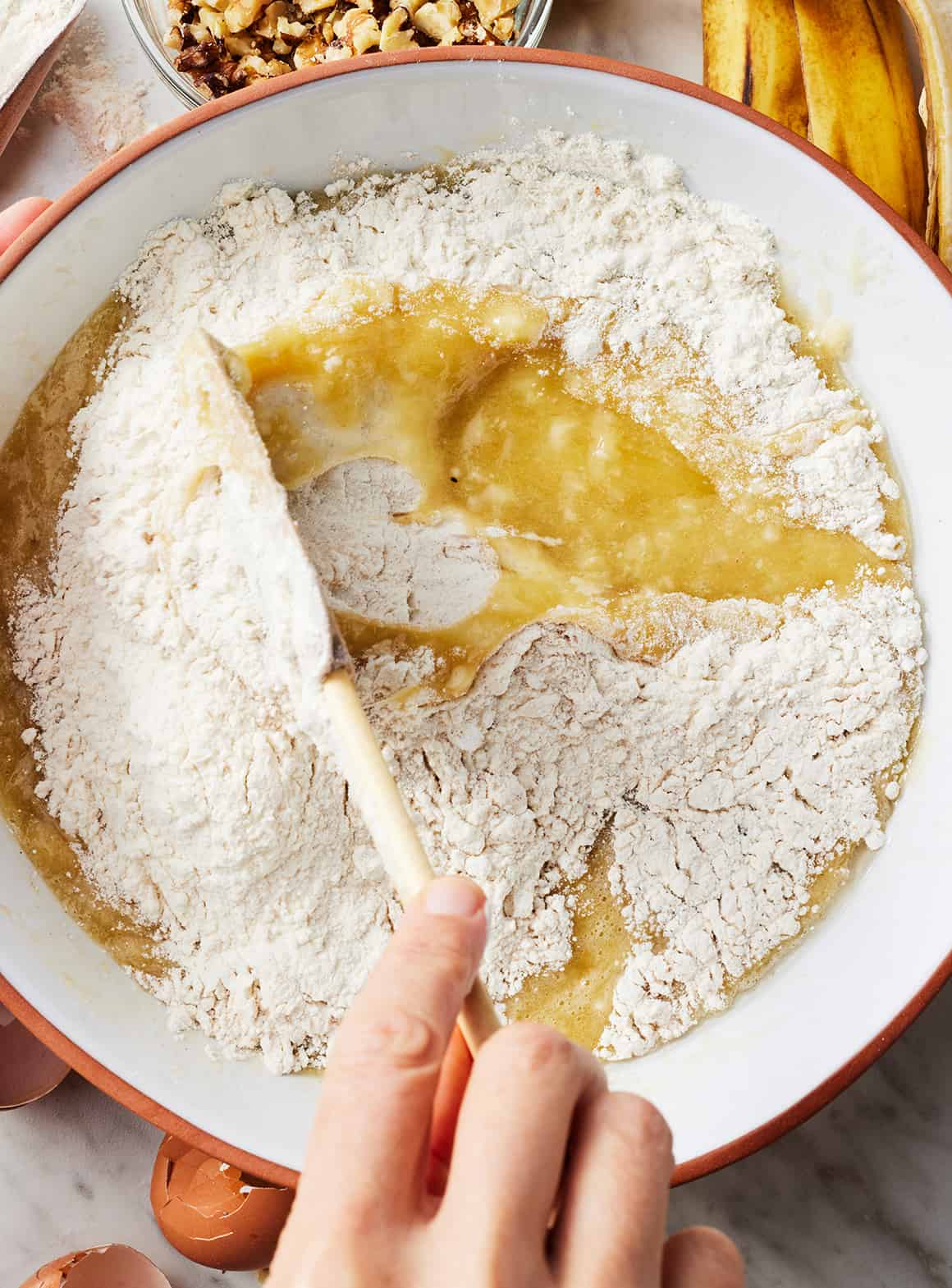 Using wooden spoon to mix wet and dry ingredients