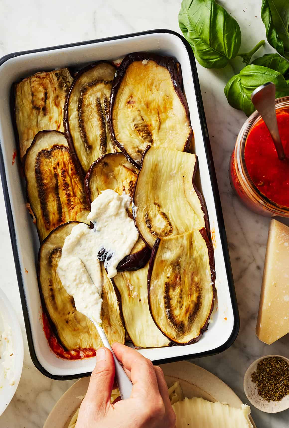 Spreading layer of cheese filling in baking dish