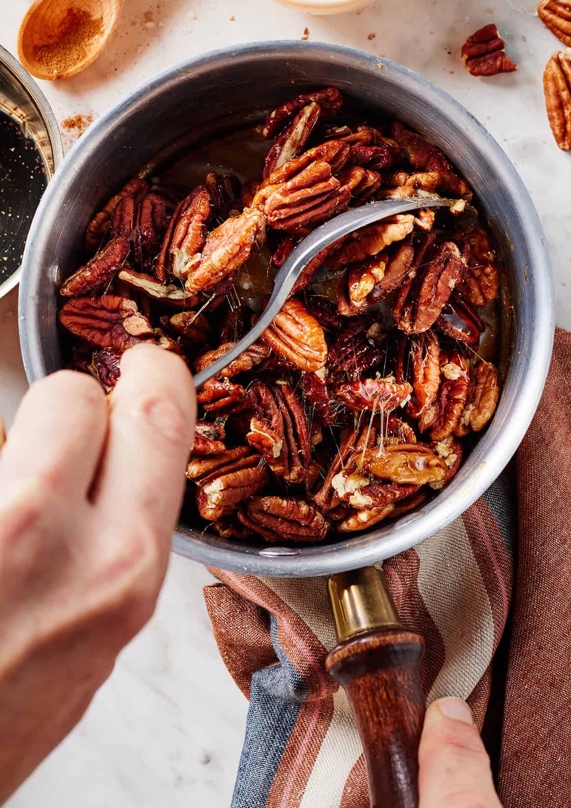 Mixing pecans with sticky brown sugar mixture in saucepan
