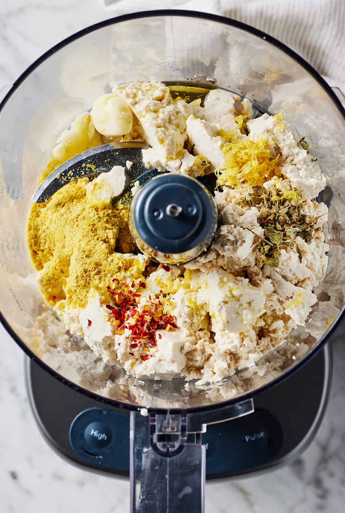 Crumbled tofu, nutritional yeast, garlic, red pepper flakes, oregano, and lemon zest in food processor