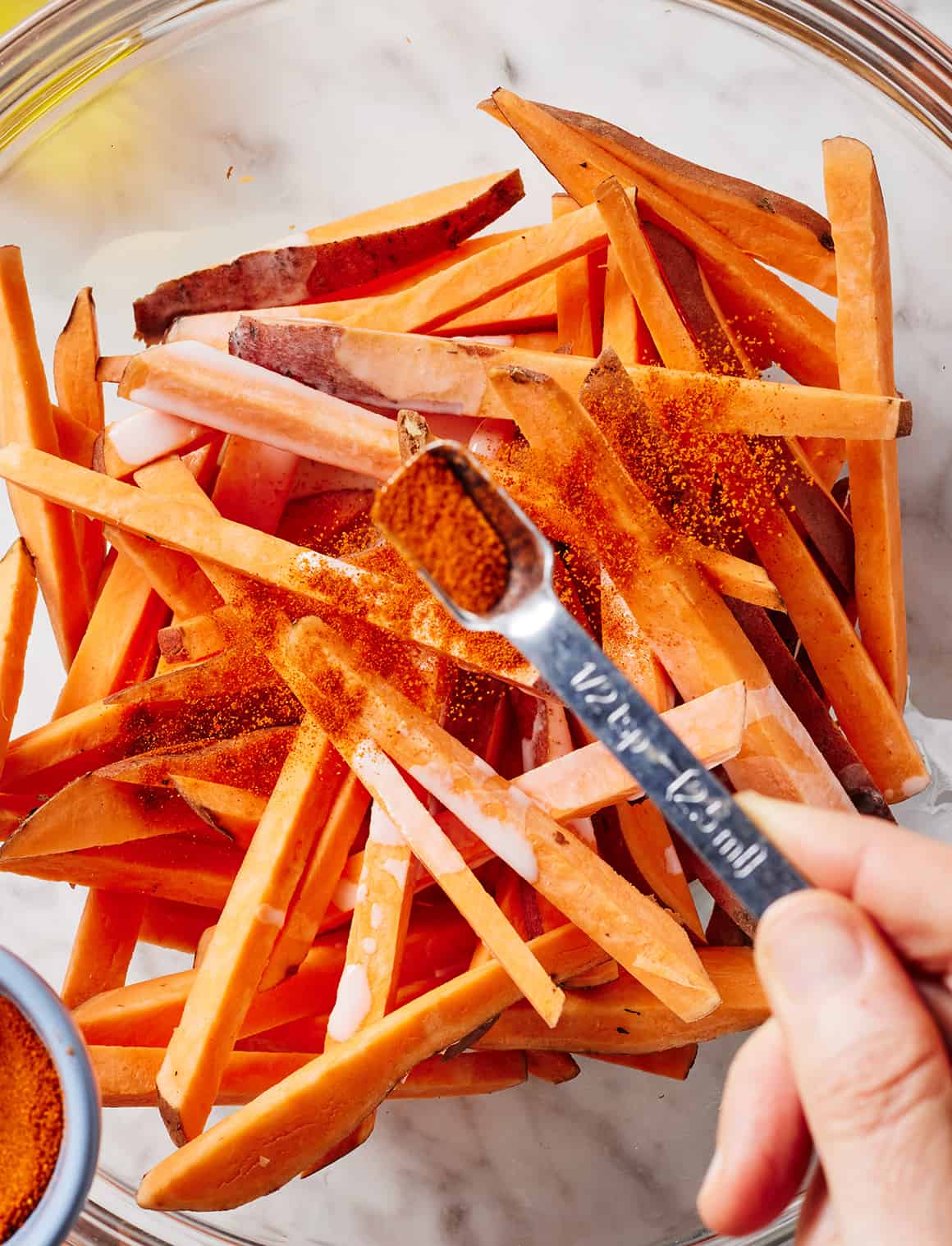 Sprinkling sweet potato fries with paprika