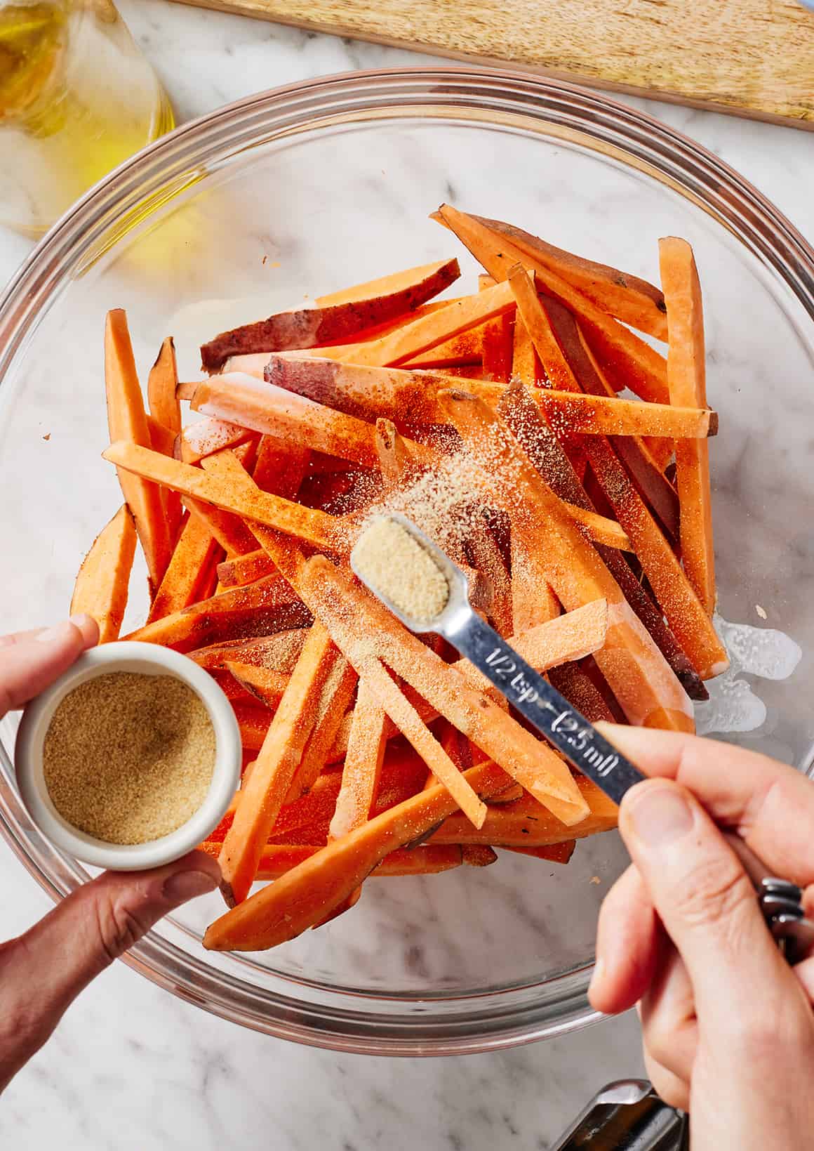 Sprinkling sweet potato fries with garlic powder