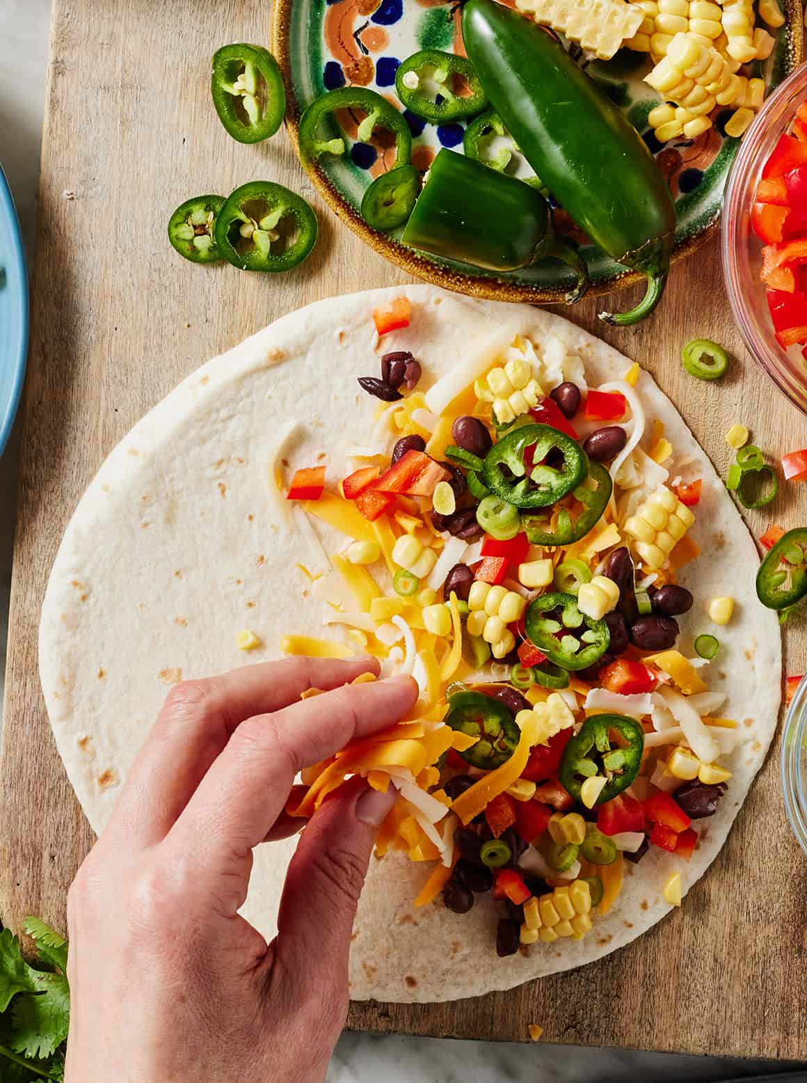 Adding cheese and veggies to tortilla