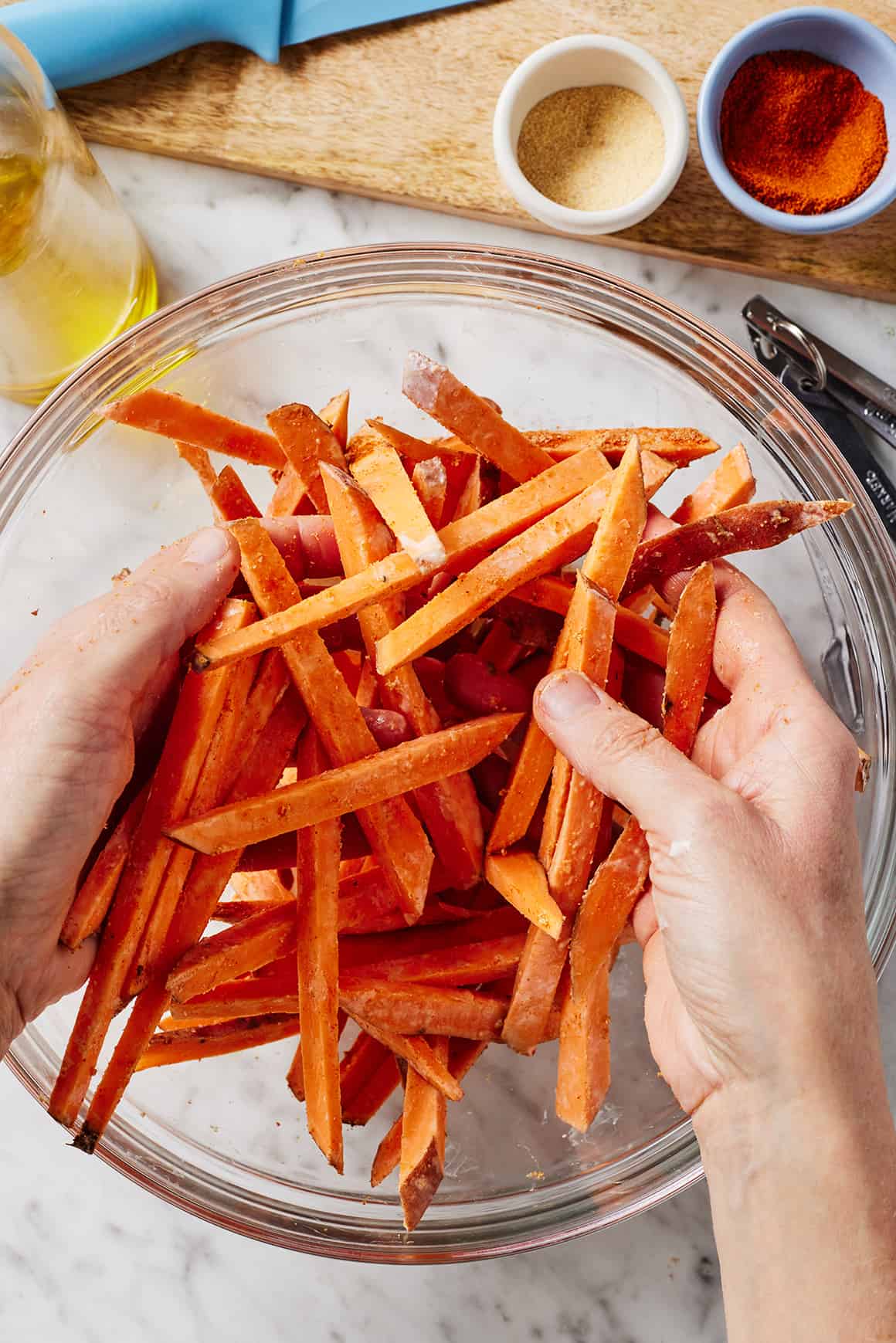 Tossing sweet potatoes with spices in glass bowl