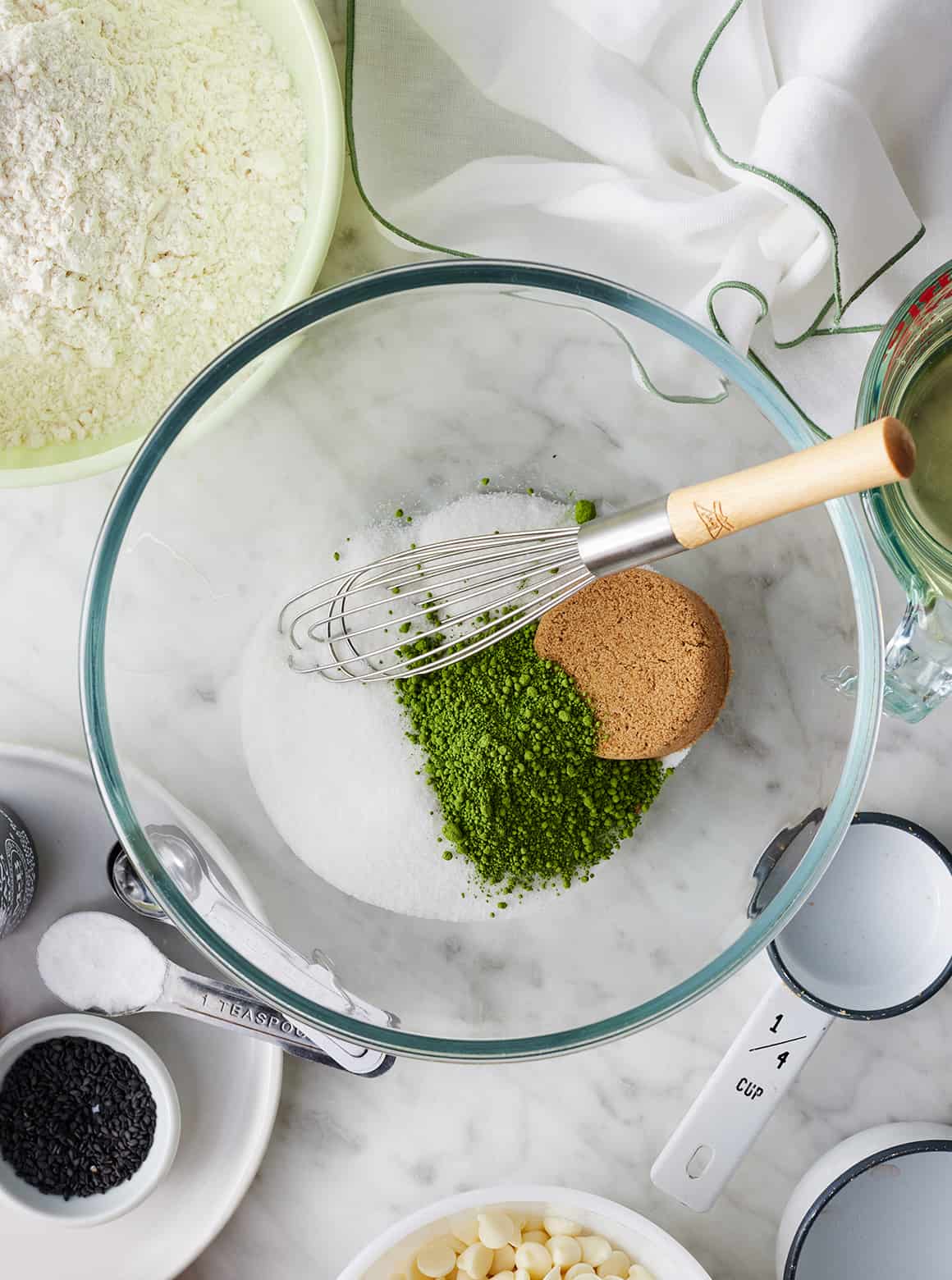 Matcha, brown sugar, and white sugar in mixing bowl with whisk