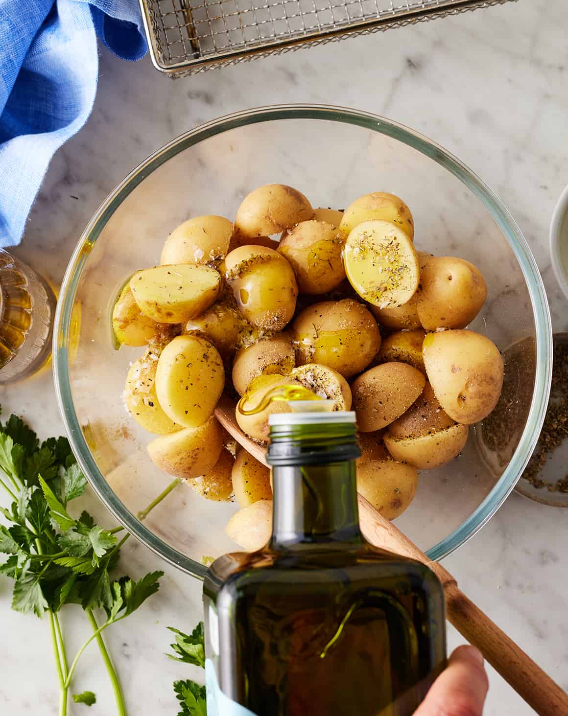 Seasoning baby potatoes in glass bowl