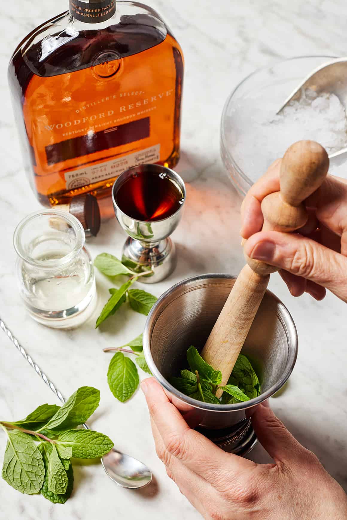 Mudding mint leaves in a julep cup