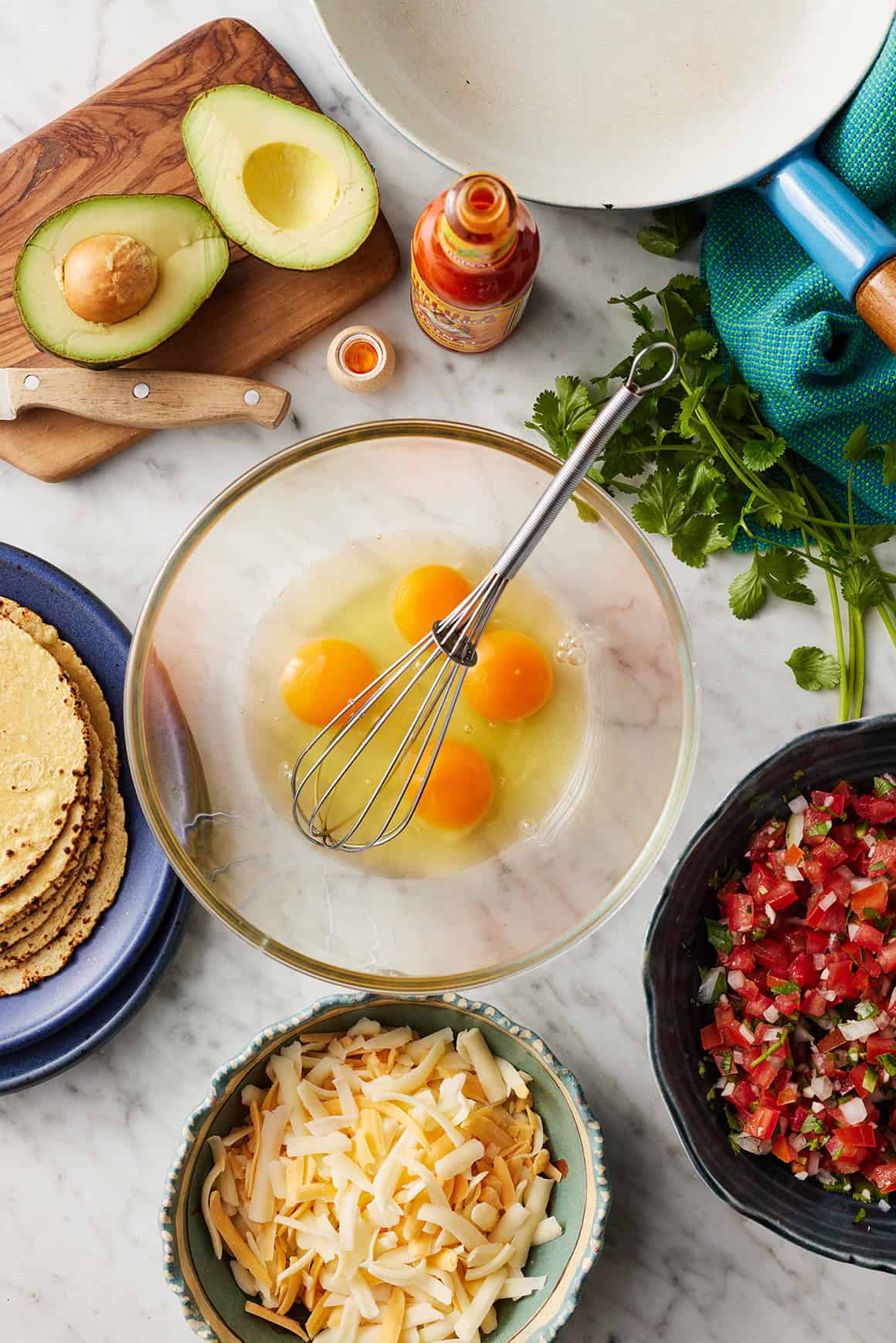 Breakfast tacos ingredients - eggs, cheese, avocado, cilantro, and pico de gallo