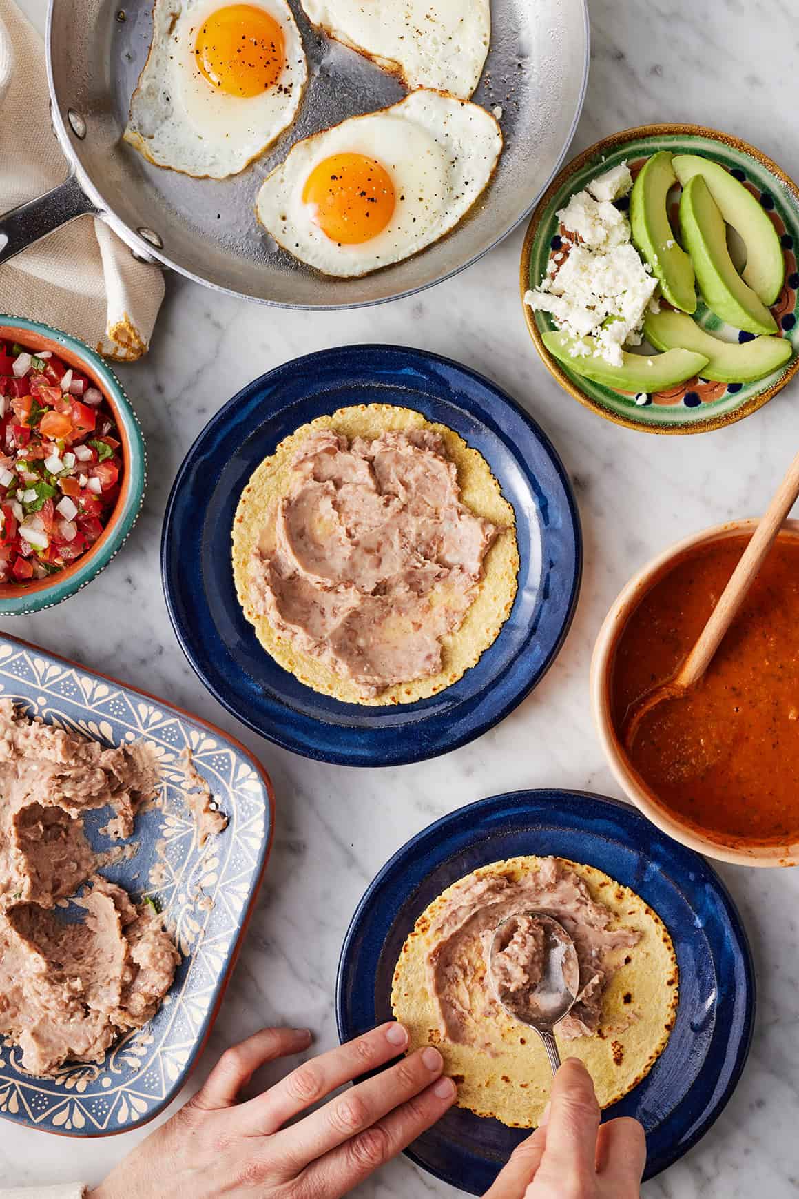 Spreading refried beans on corn tortilla