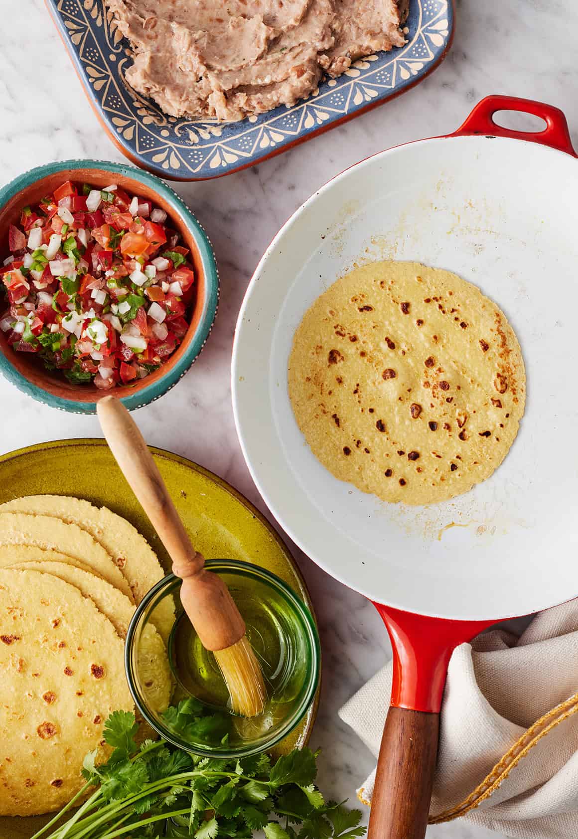 Toasting tortilla in a skillet with refried beans and pico de gallo nearby