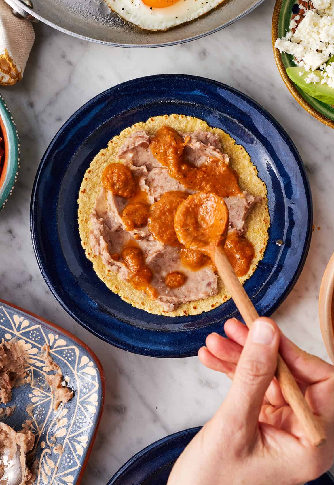 Topping refried beans with ranchero sauce
