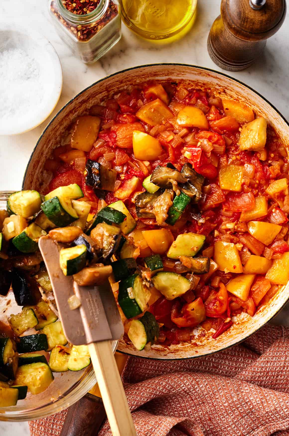 Adding summer vegetables to skillet with tomatoes